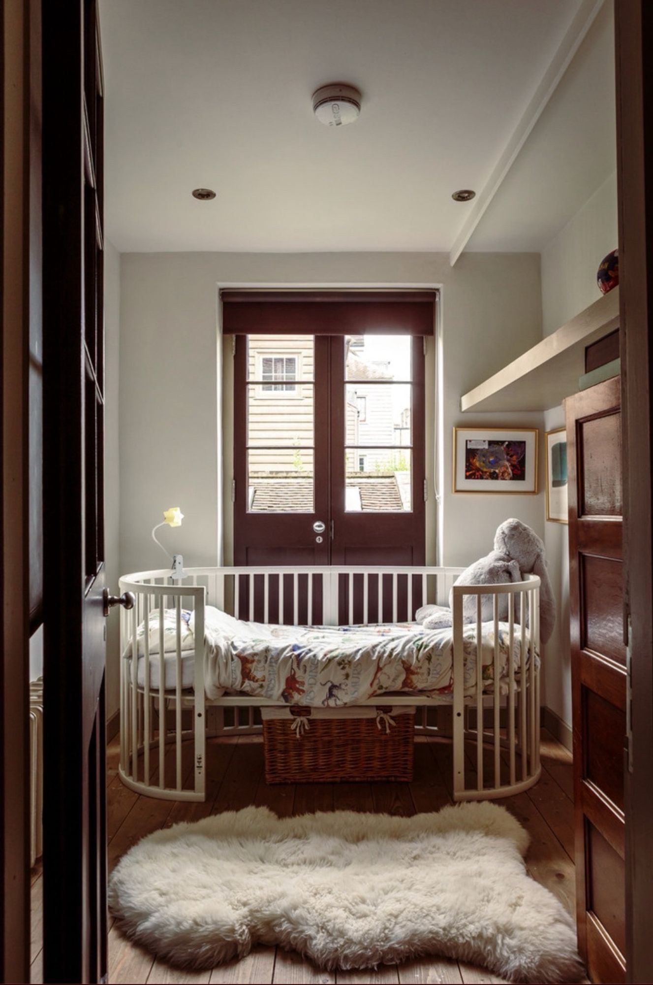 Child’s room with an oval crib and French doors letting in bleak light. A sheepskin on the floor presumably hides a huge bloodstain. It’s in perfect taste and creepy AF.