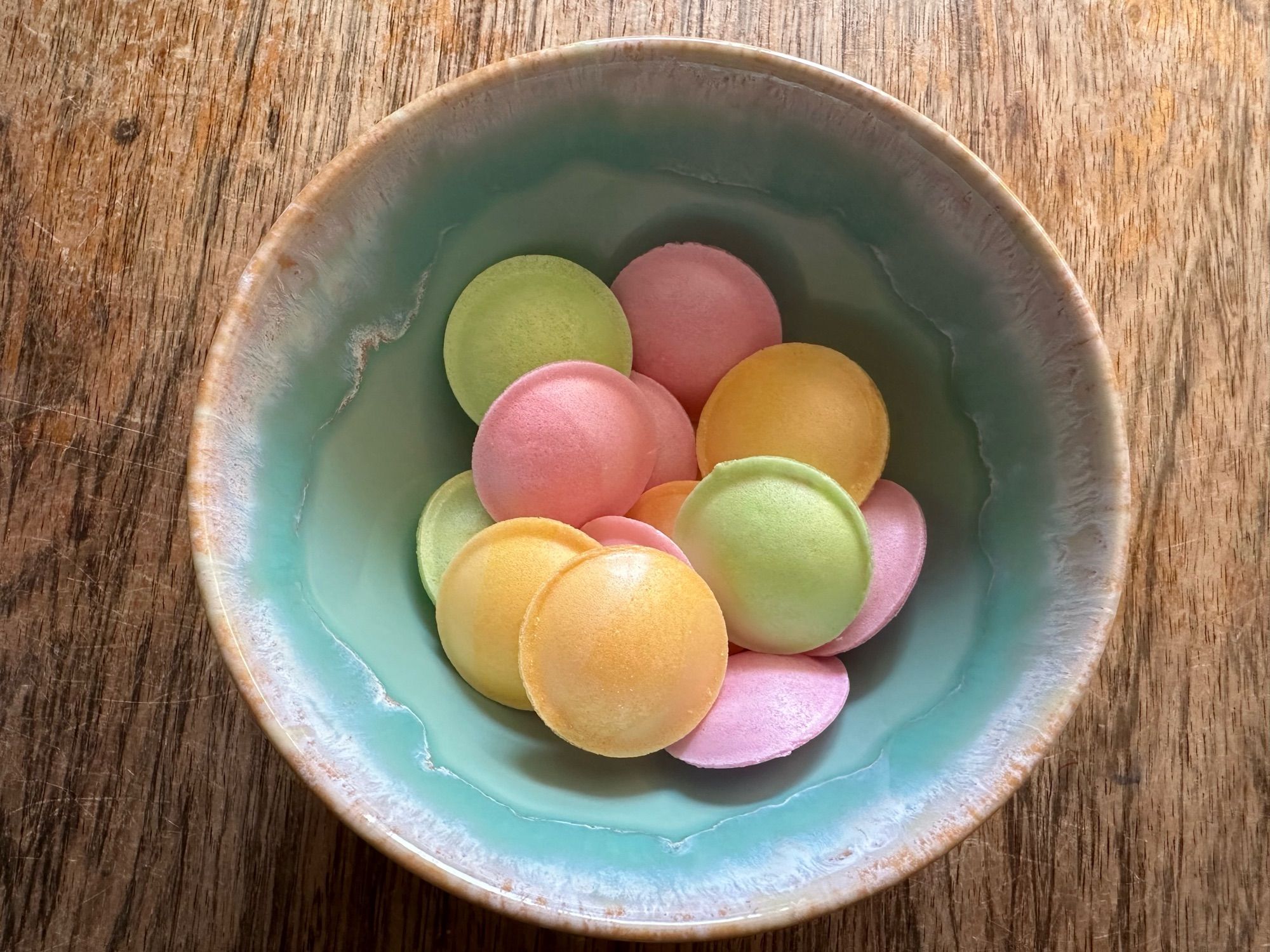 Grünliche Schüssel mit bunten Ufos - Oblaten mit Brausepulverfüllung in orange, rosa und grün.