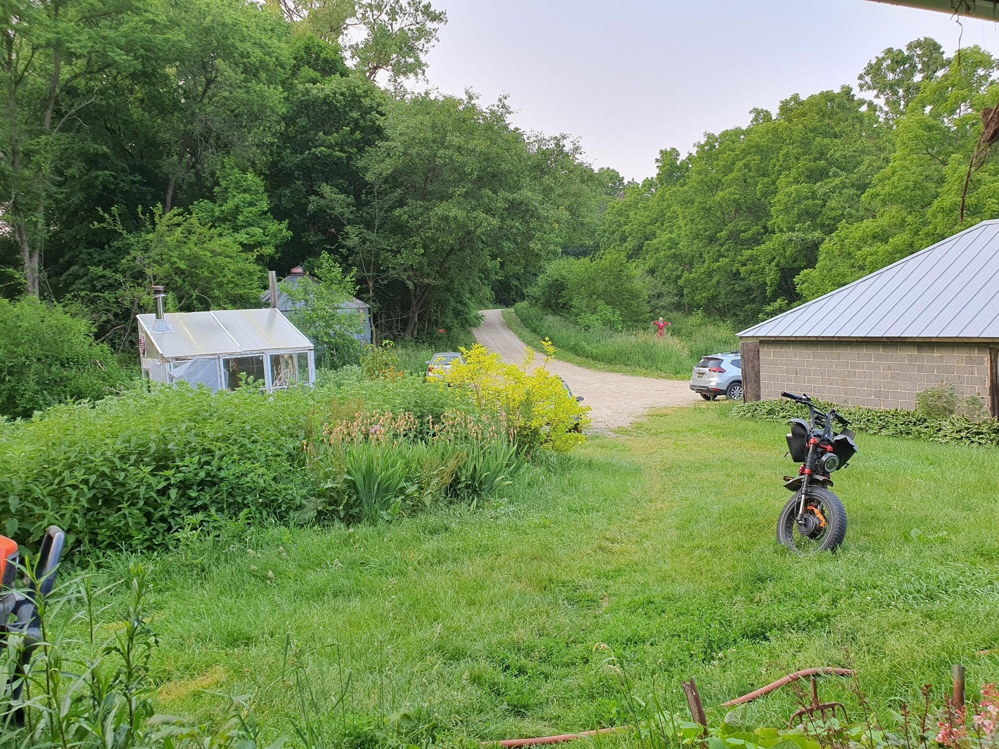 A gravel driveway with some cars and green space