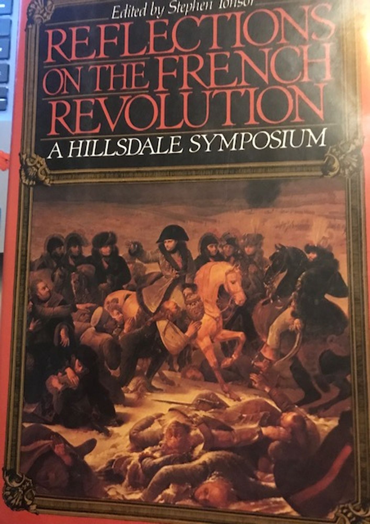 The cover of the book "Reflections of the French Revolution: A Hillsdale Symposium," Stephen Tonsor editor. The cover features a painting of Napolean riding his horse surrounded by soldiers. A few corpses on in the foreground.