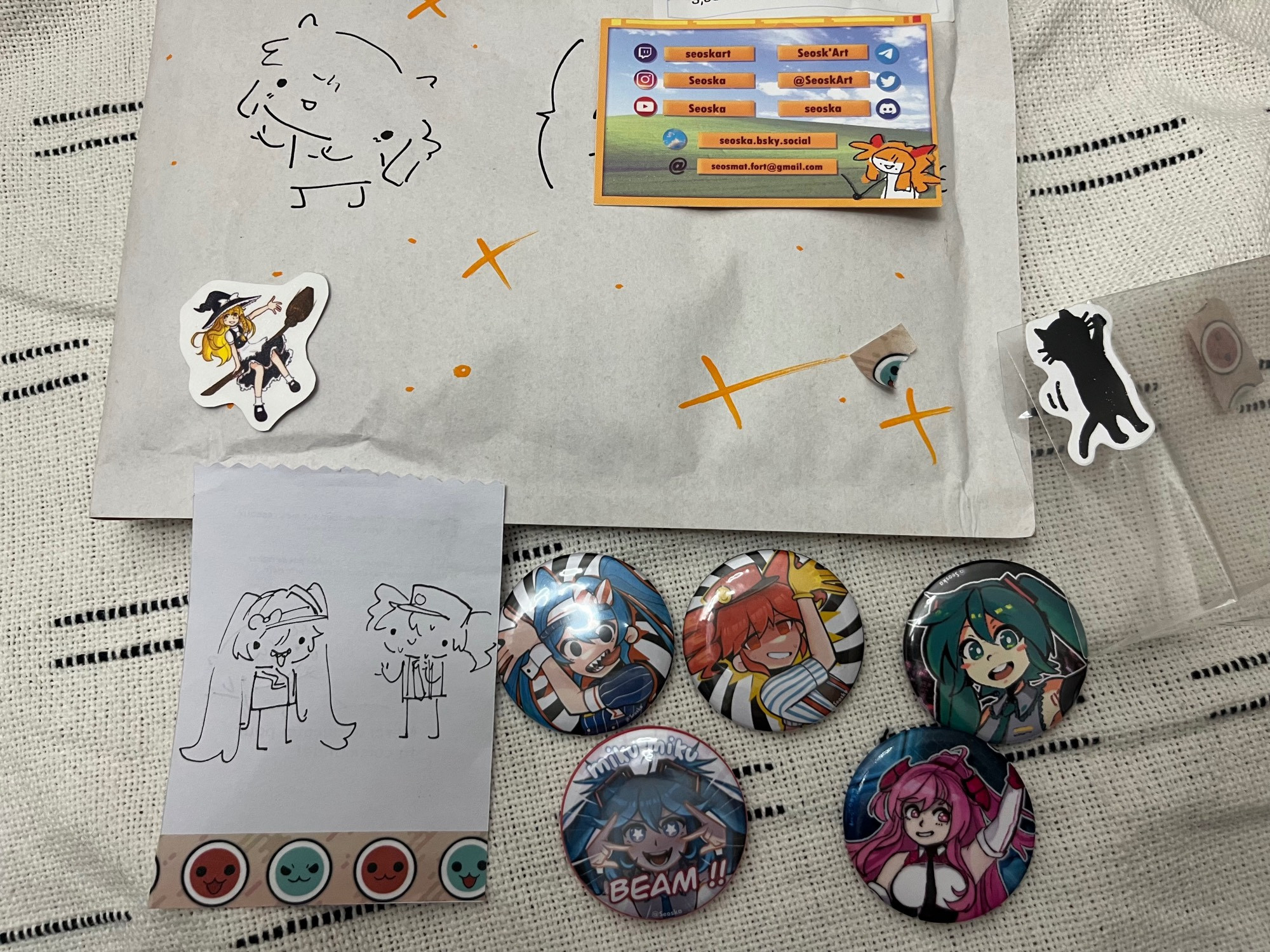 Magnifique enveloppe bulle avec un petit personnage doodle dessus et des étoiles. Ainsi que deux stikers un de marisa de touhou et un chat qui gratte a la fenêtre en hurlant(selon mon interprétation), accompagné de 5 magnifiques pins un miku miku beam!! Un de miku, et un couple de pins miku teto de la chanson mesmerizer et un autre d’un perso de jeu de rythme.
Le tout est magnifique.