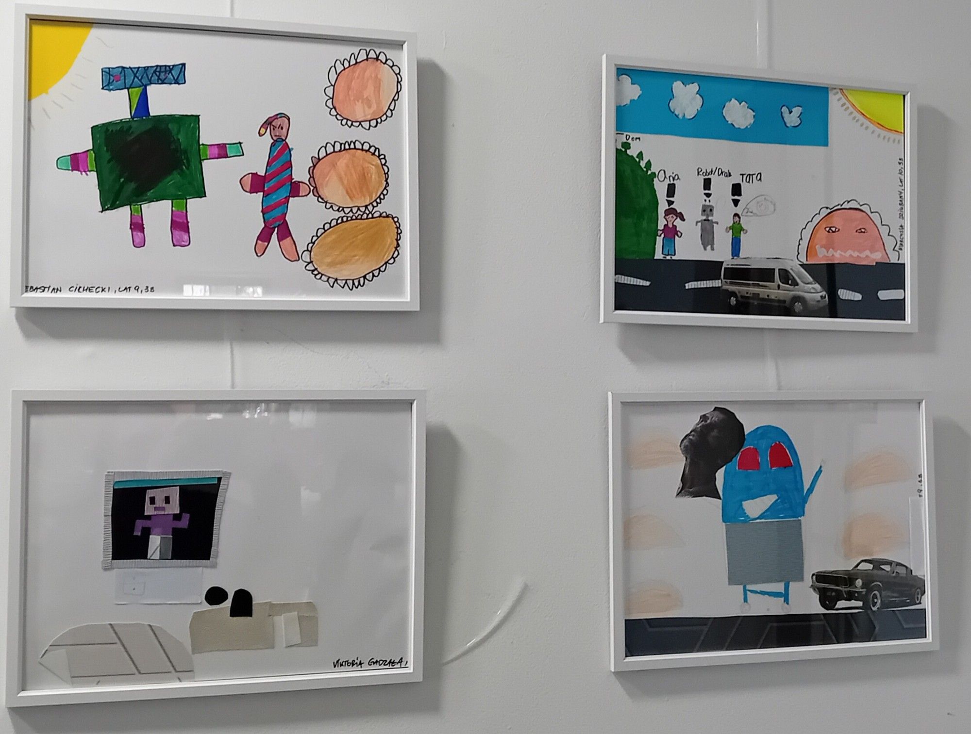 Four children's illustrations, framed and mounted on a wall, showing their varying interpretations of Drac, the giant pierogi-making robot.