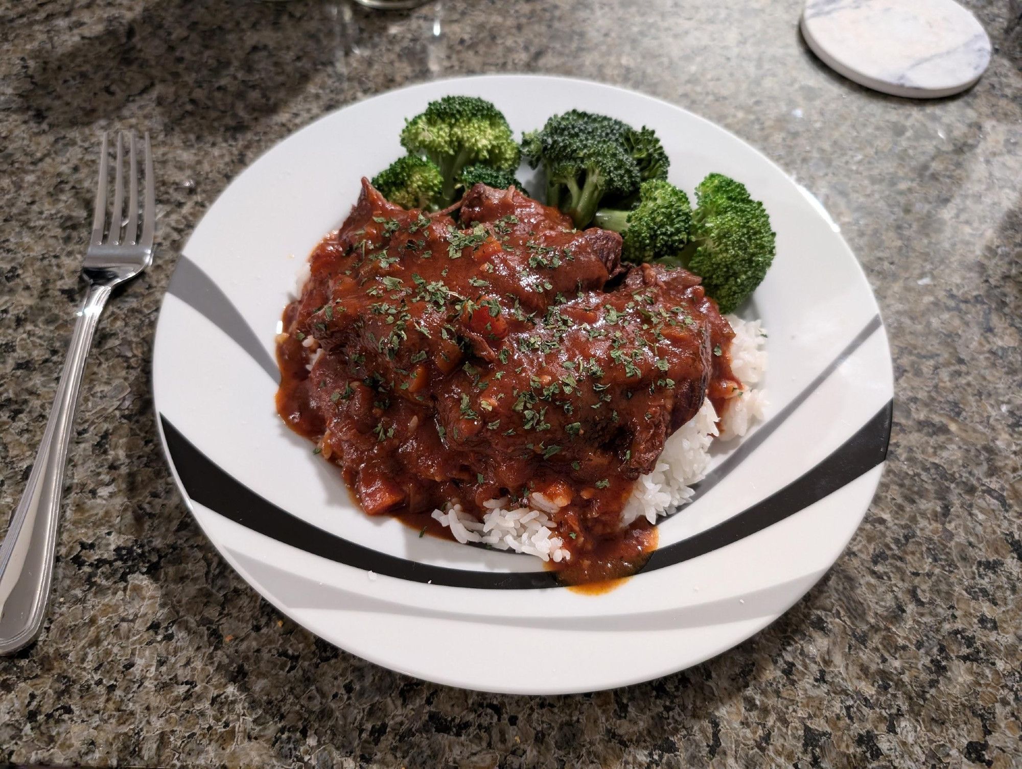 A photograph of a plate of braised lamb shanks over rice.