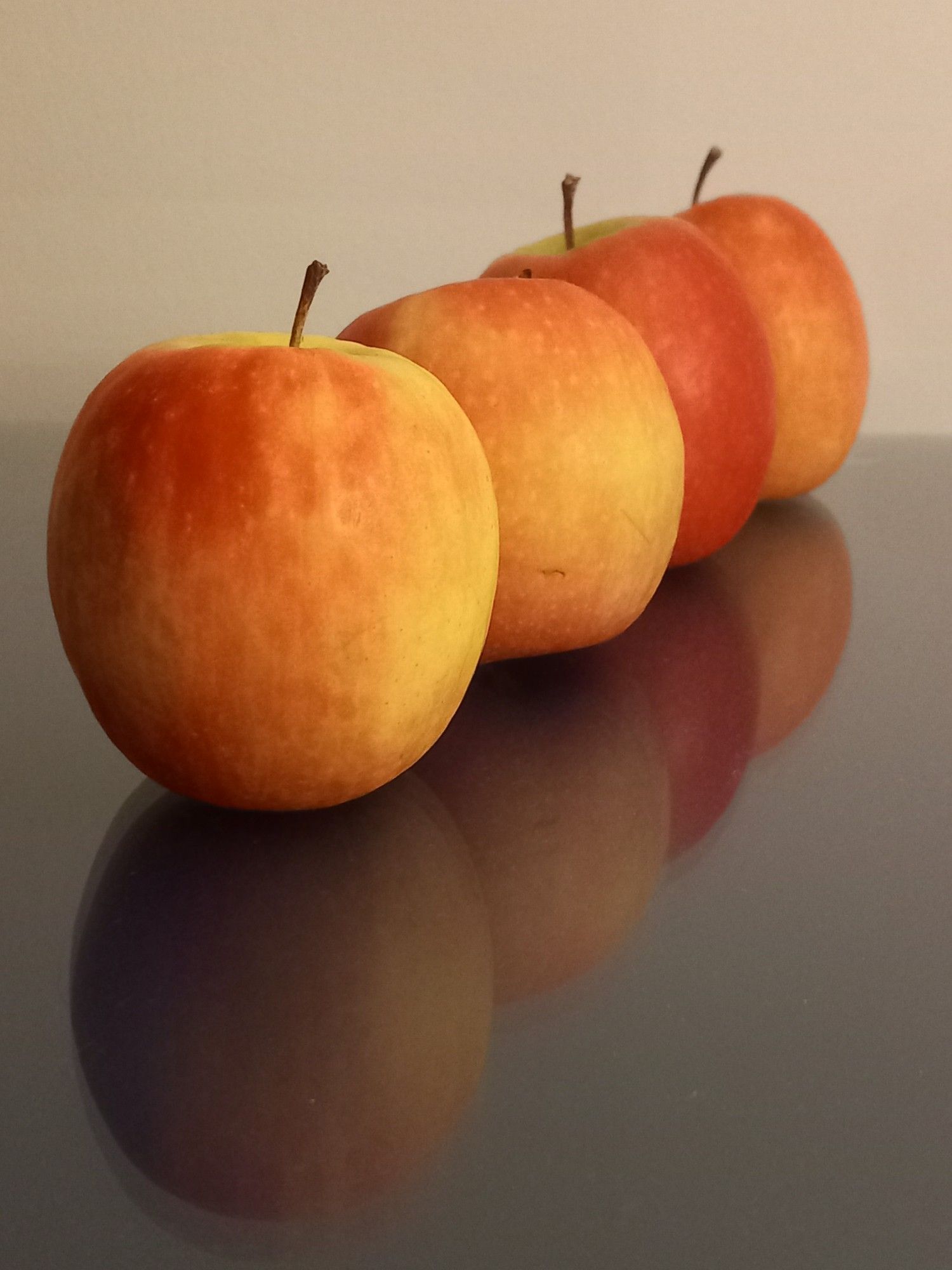 Vier Äpfel in Reihe mit Spiegelbild auf Glas - row of four apples with reflection on glas