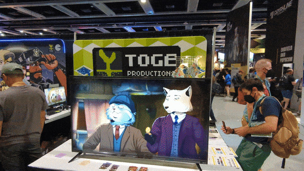 A GIF panning from right to left slowly, showing the full Toge Productions booth at PAX West. Nate, the editor-in-chief of VGG, sits in a chair demoing Whisper Mountain Outbreak and he chats and gestures with a Toge team member standing to his right.