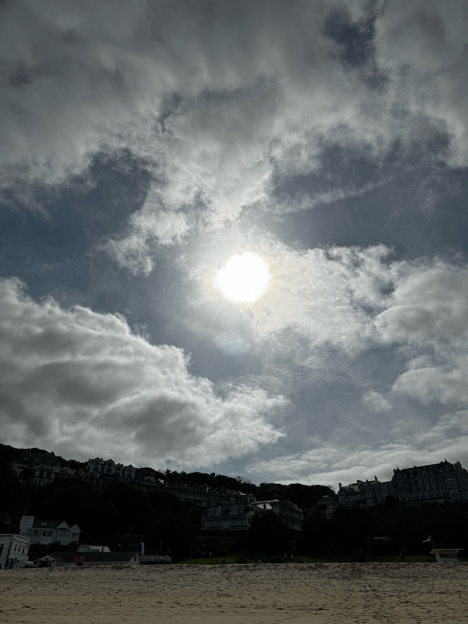 The sun shining through clouds over a beach