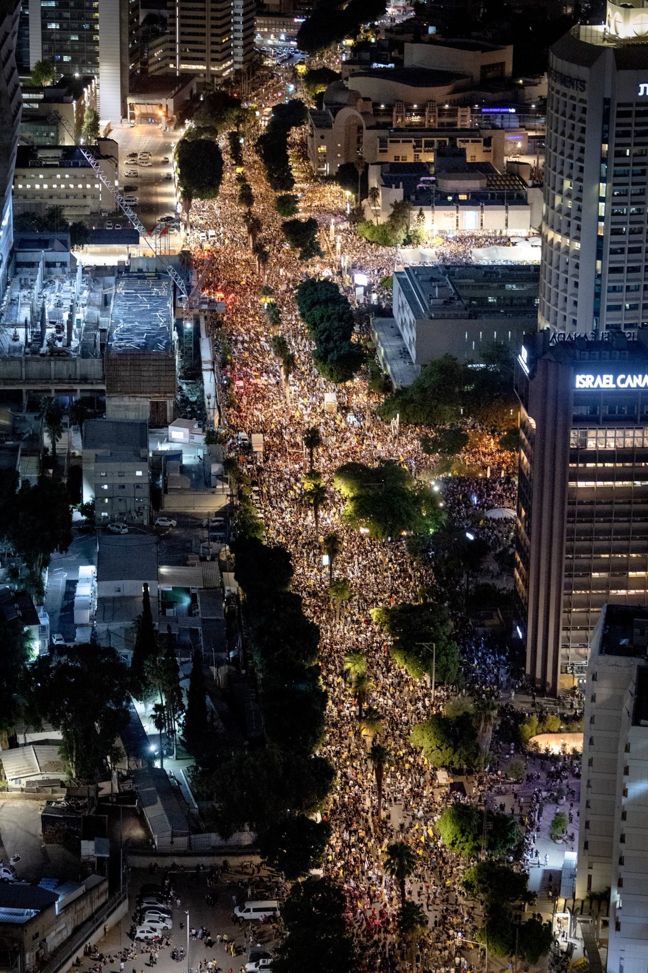 Crowds stream along a street at night 