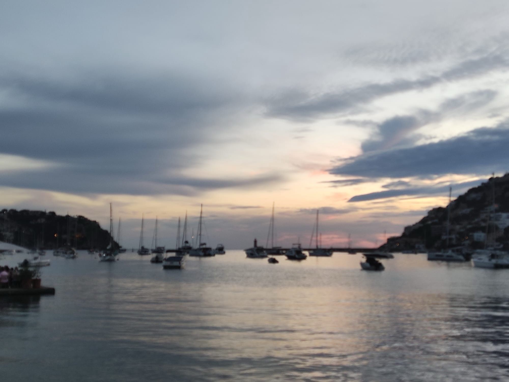 Pastel and grey-ish colored sunset over a harbor scenery with sailboats