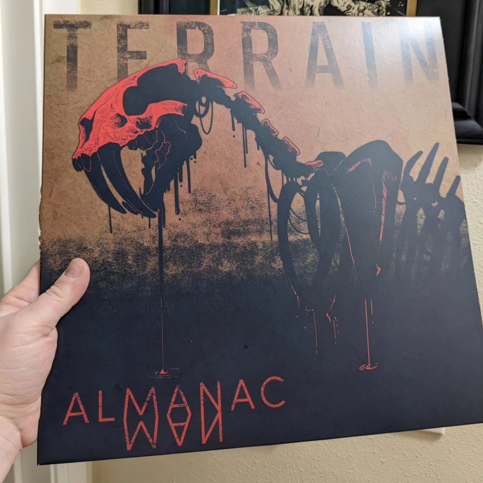 Almanac Man's cover for their album, Terrain featuring my art of a red skulled sabertooth skeleton emerging from a tar pit.