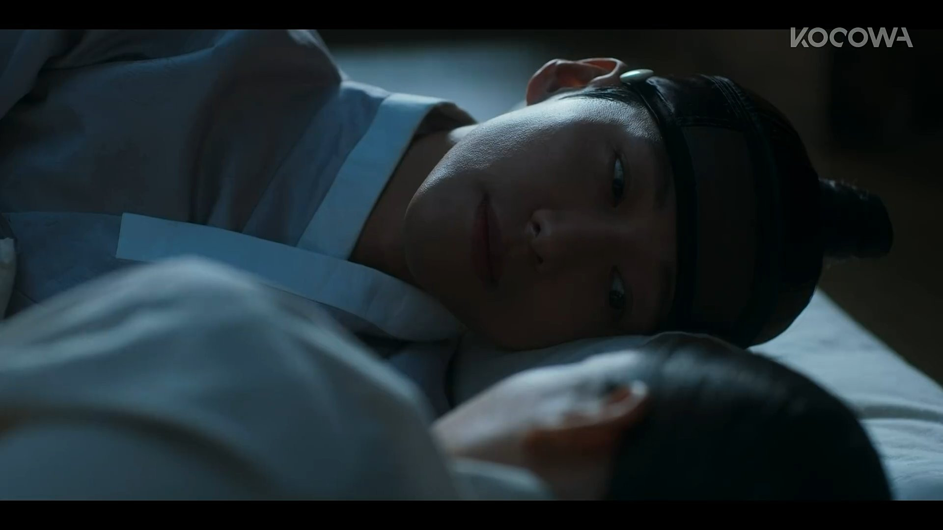 A screenshot from the drama My Dearest. Lee Jang Hyeon gazes at an asleep Gil Chae.