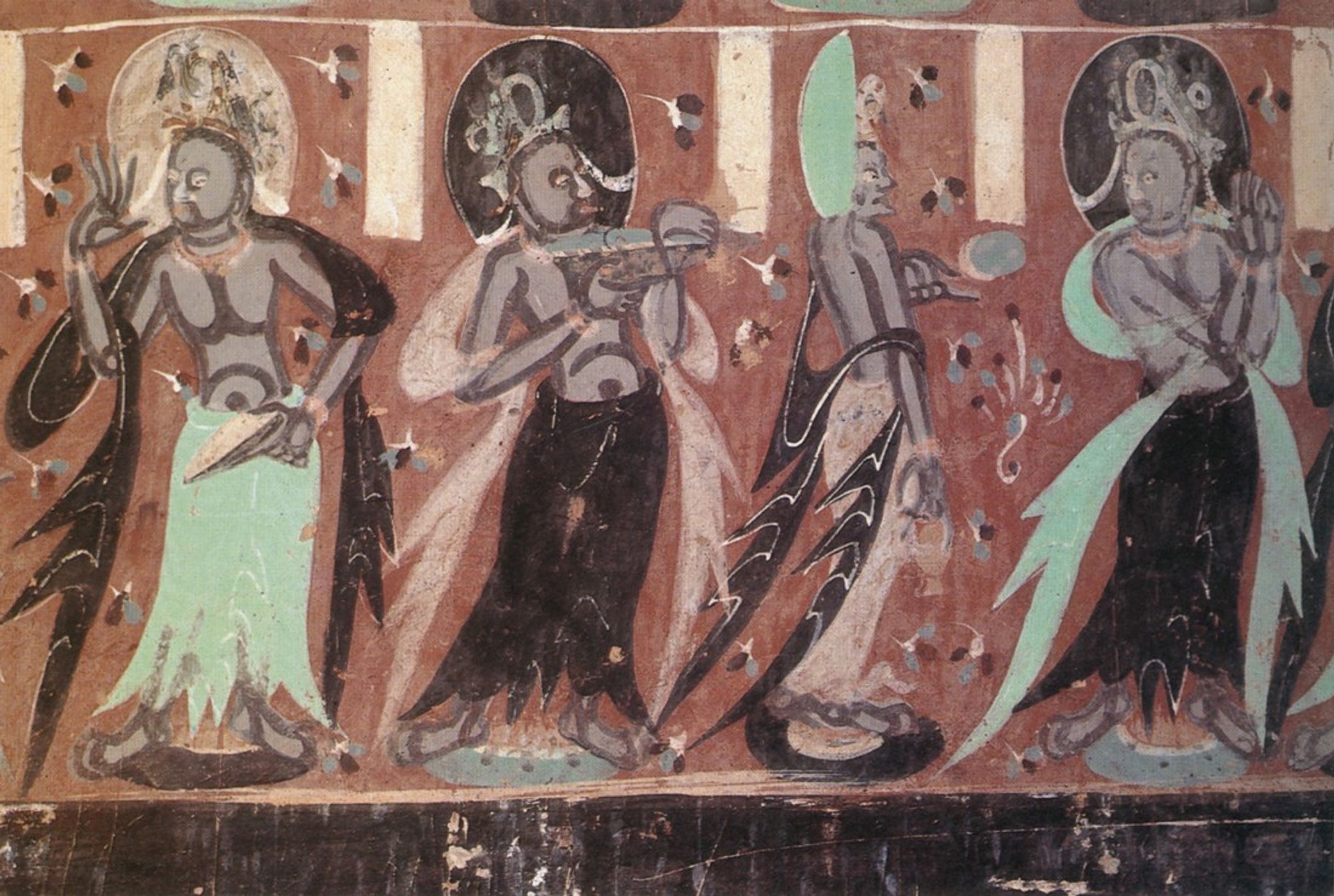 Detail of a cave temple from the Dunhuang caves in China - showing a row of standing bodhisattvas wearing long skirts and flowing scarves. They are mostly facing front and have halos around their heads, but one is turned to the side and the halo has turned with him, as if it's a plate stuck to the back of his head.