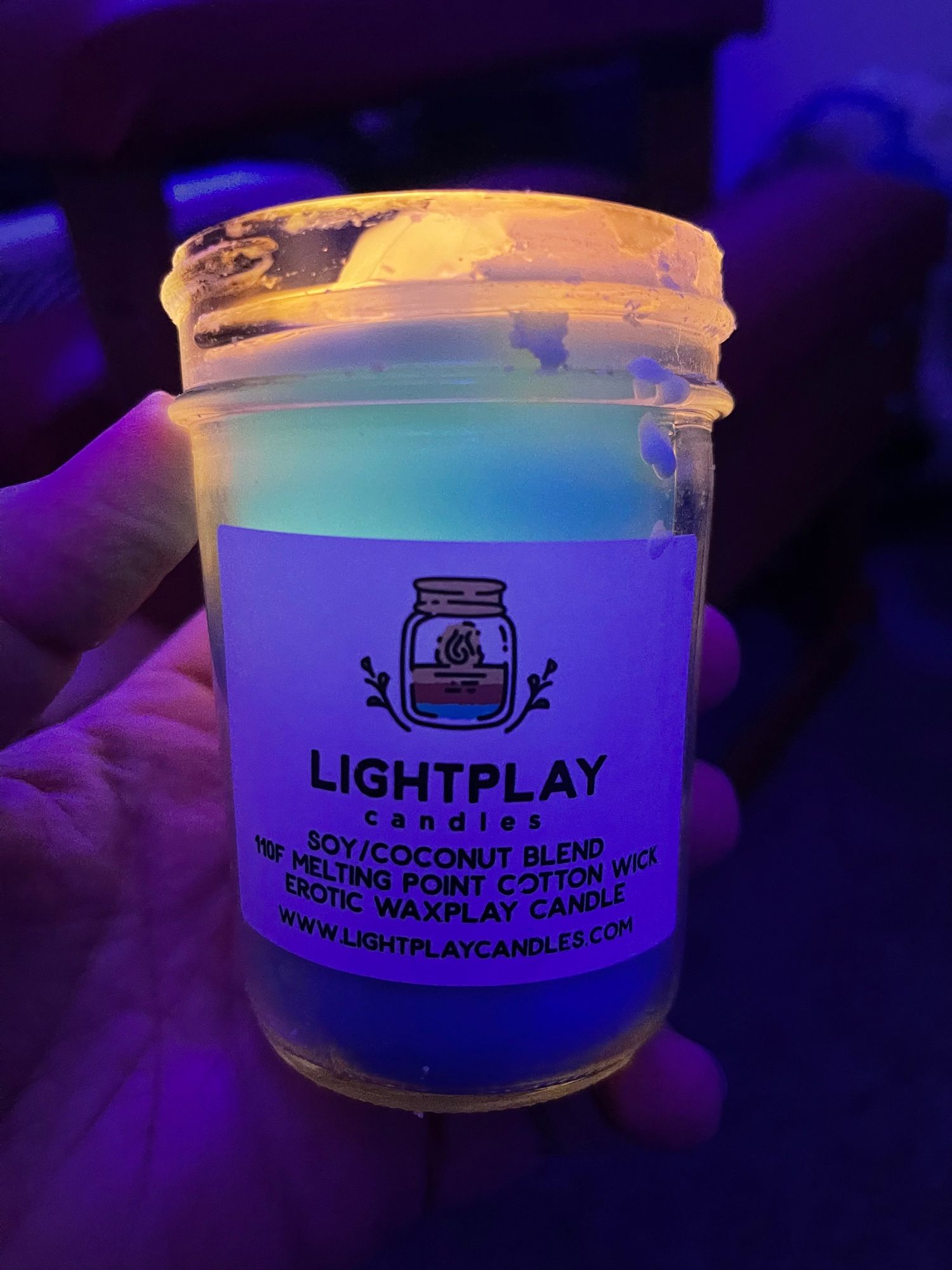 Riley holding a Lightplay UV blue candle for wax play