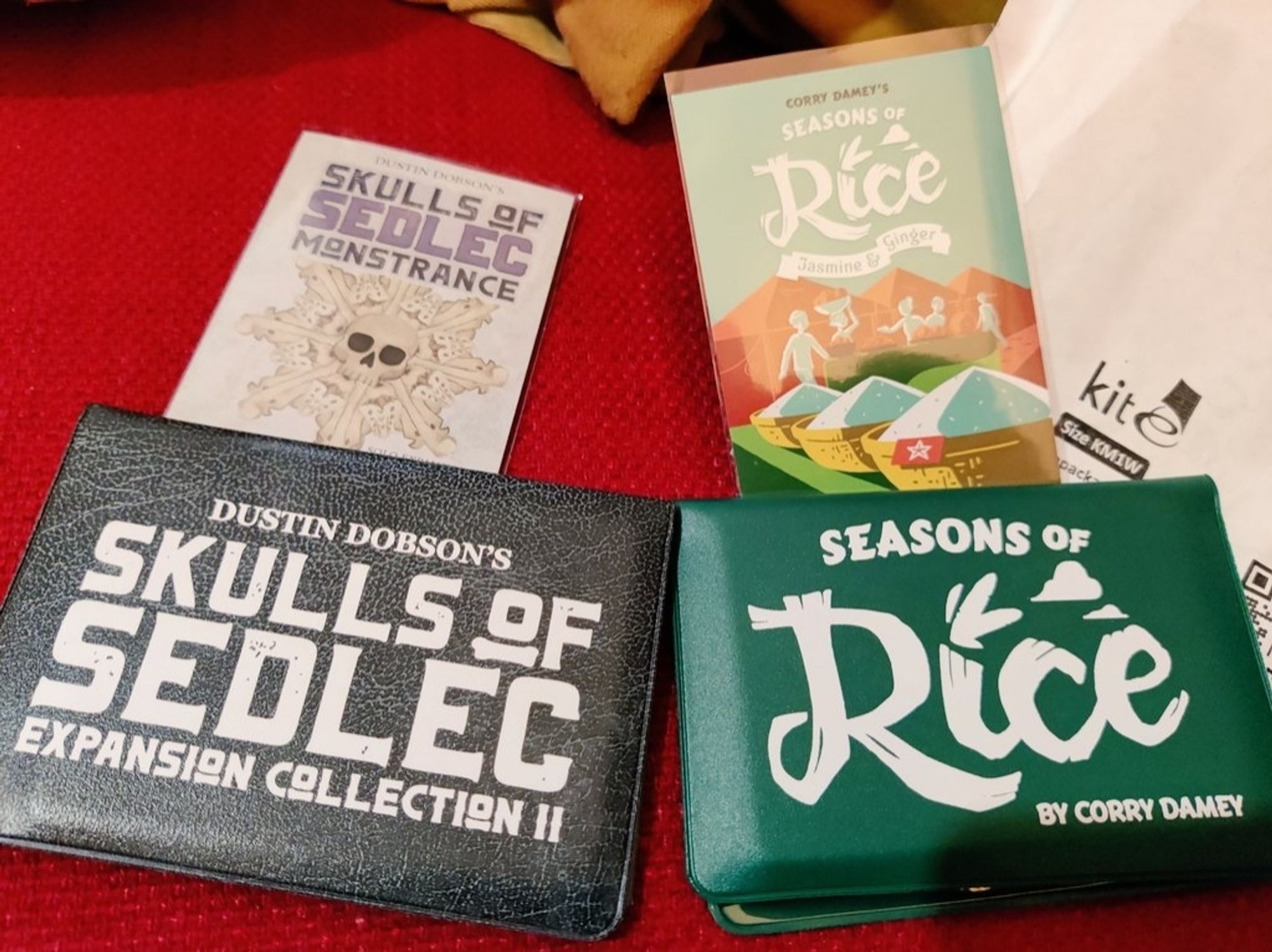 Two games in vinyl wallets. Left: Skulls of Sedlec, the expansion. Right: Seasons of Rice