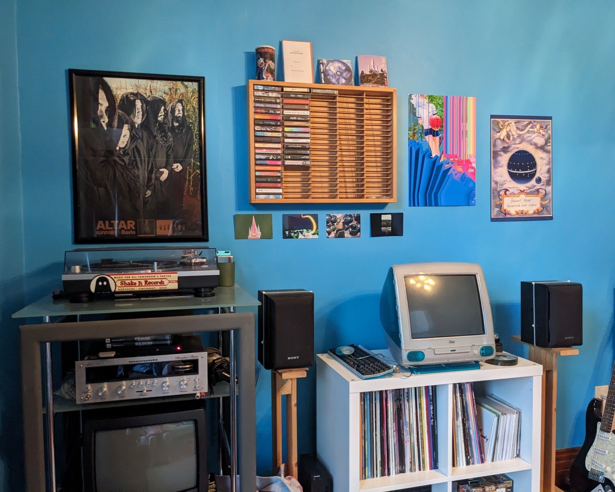 Stereo rack sitting next to record shelf with blueberry iMac G3 on top. Cassette shelf and posters on the wall