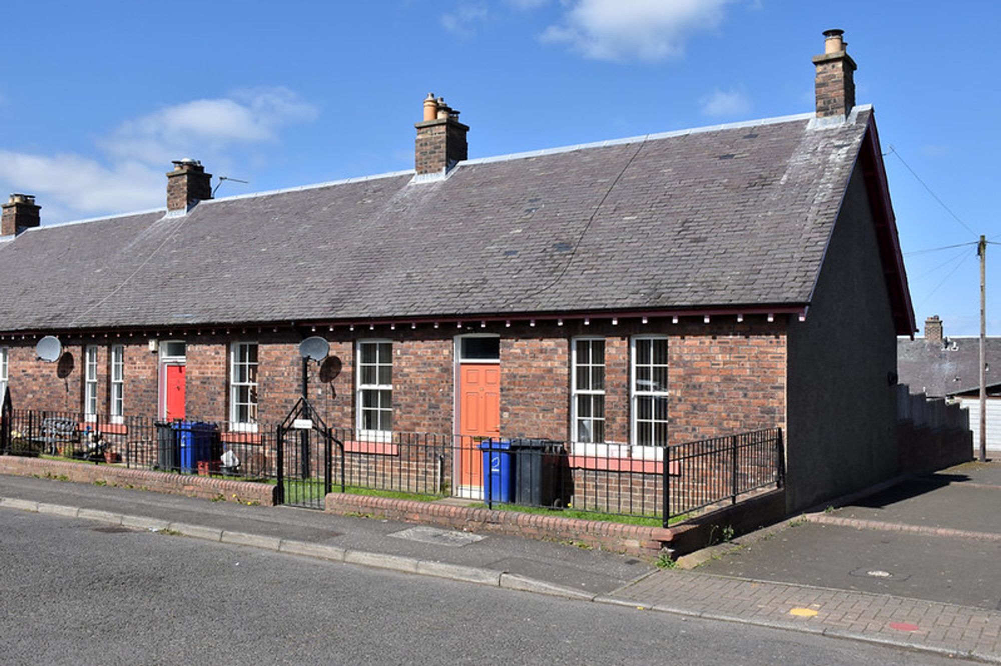 Row of terraced miners' cottages in red brick with slate roofs.  Chimneys and small front gardens.