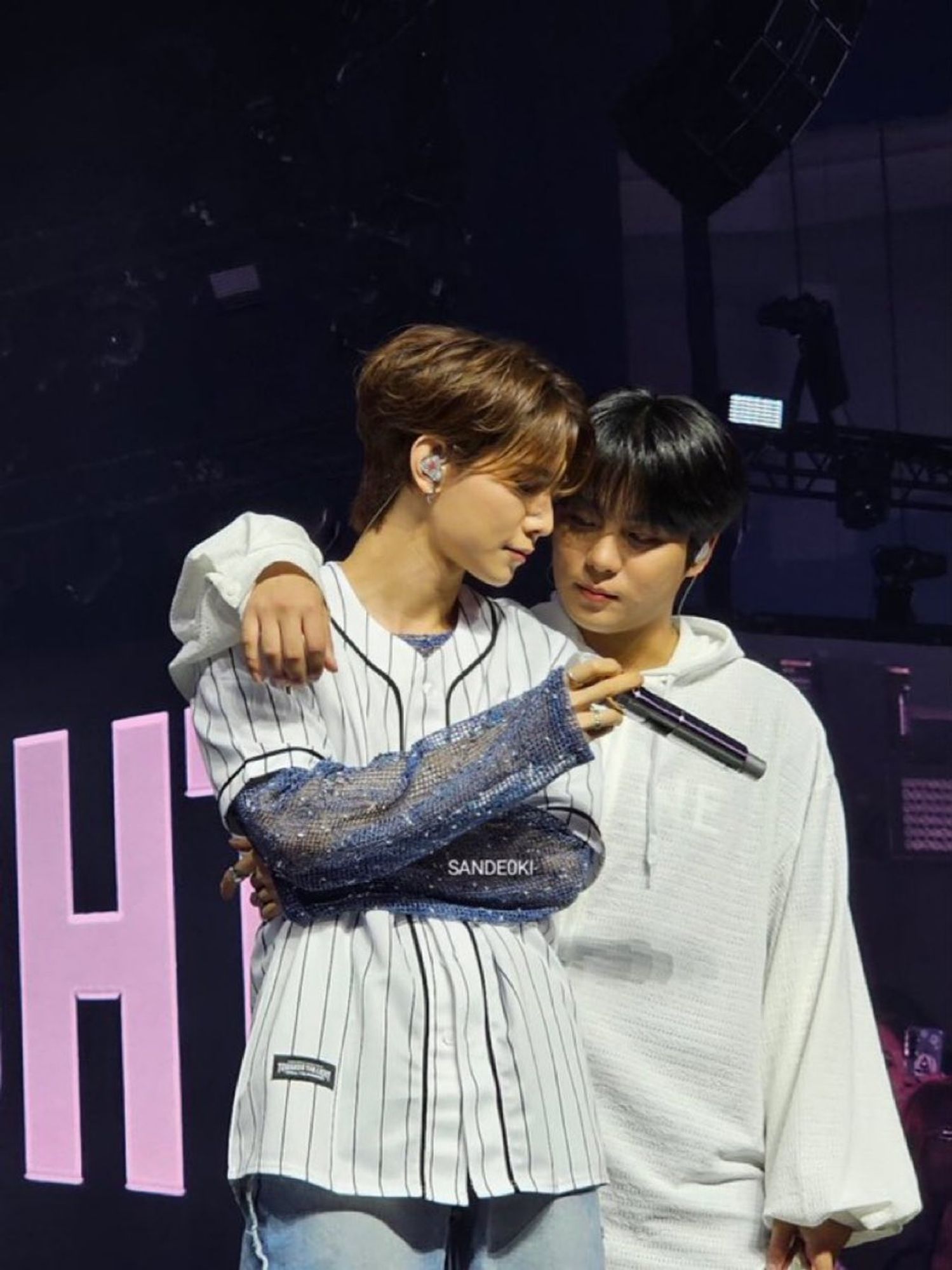 kpop group ateez member choi jongho with his arm around the shoulders of group member kang yeosang