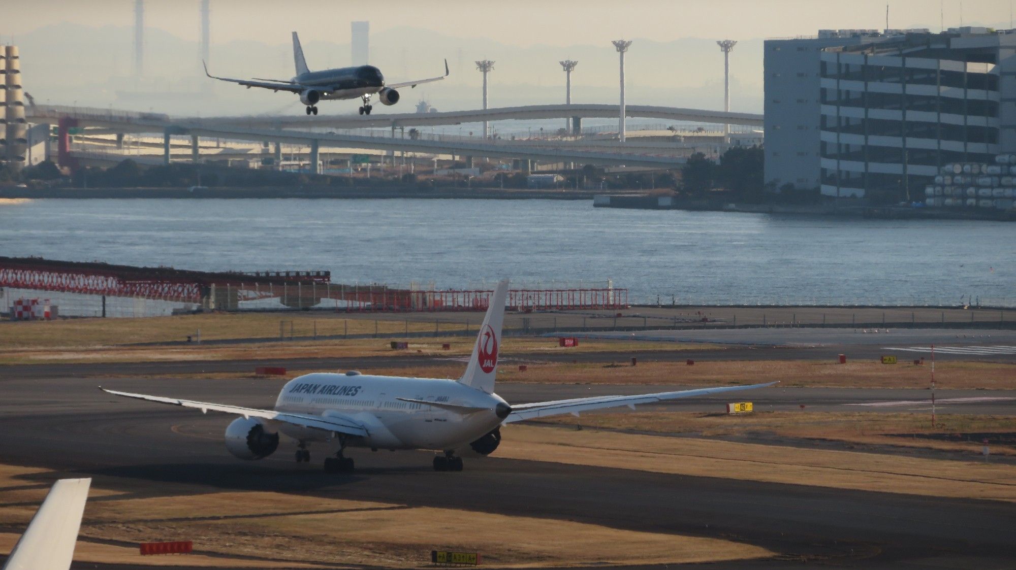 羽田空港にて、着陸しようとしているスターフライヤーと滑走路を移動するJAL機。