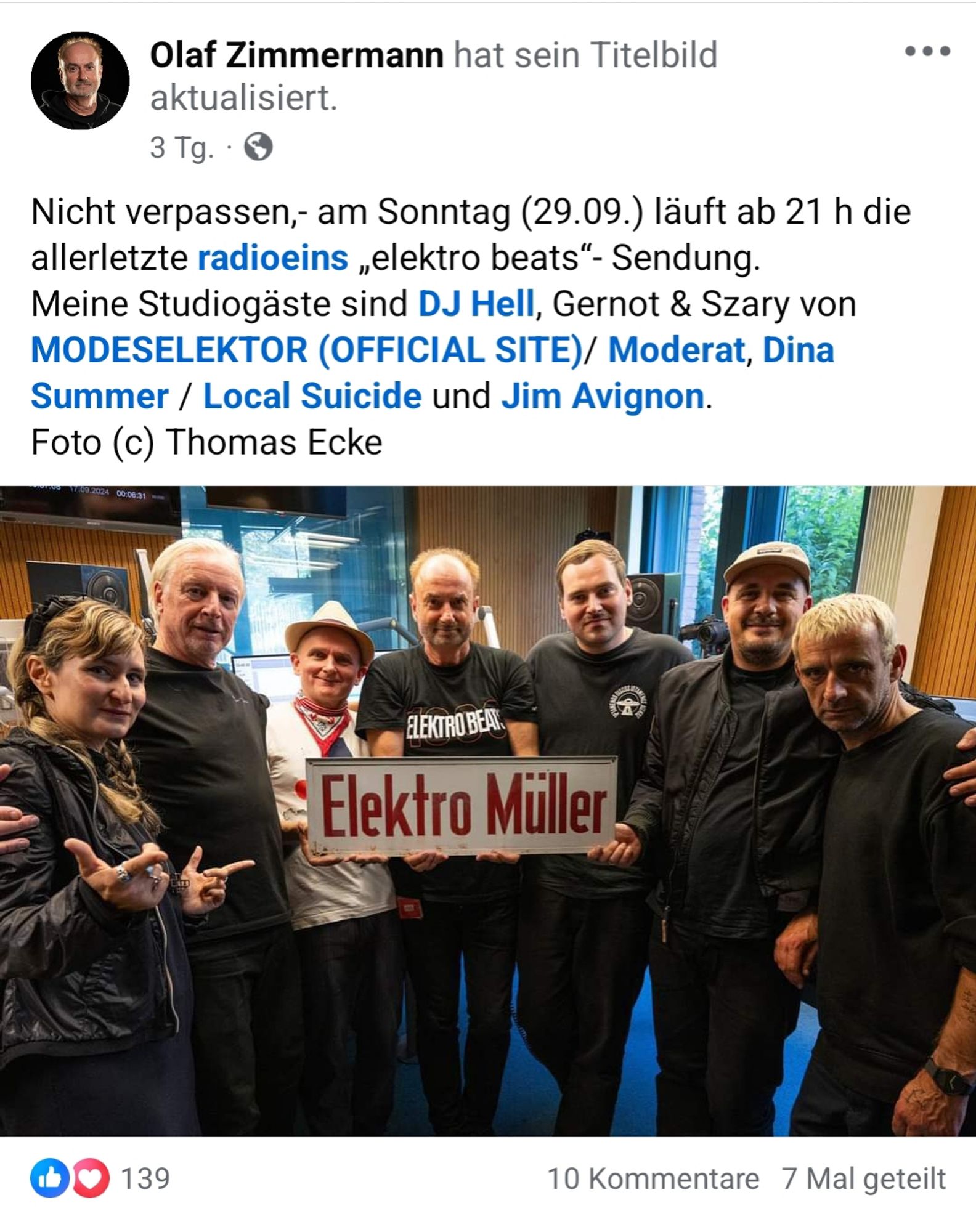 Screenshot eines Posts der Facebookseite von Radiomoderator Olaf Zimmermann.
Text mit Bild.
Text:
"Nicht verpassen,- am Sonntag (29.09.) läuft ab 21 h die allerletzte radioeins „elektro beats“- Sendung.
Meine Studiogäste sind DJ Hell, Gernot & Szary von MODESELEKTOR (OFFICIAL SITE)/ Moderat, Dina Summer / Local Suicide und Jim Avignon.
Foto (c) Thomas Ecke"

Bild zeigt 7 Personen, die nebeneinander stehen.
Augenscheinlich in einer Art Studio aufgenommen.
Es handelt sich um die im Text erwähnten Künstler.
In der Mitte der Reihe Olaf Zimmermann.
Er hält, zusammen mit zwei anderen Gästen, ein altes Emaille-Schild vor sich.
Das Schild ist länglich, weiß mit roter Schrift.
Der Schriftzug, in schmaler serifenloser Druckschrift: "Elektro Müller"