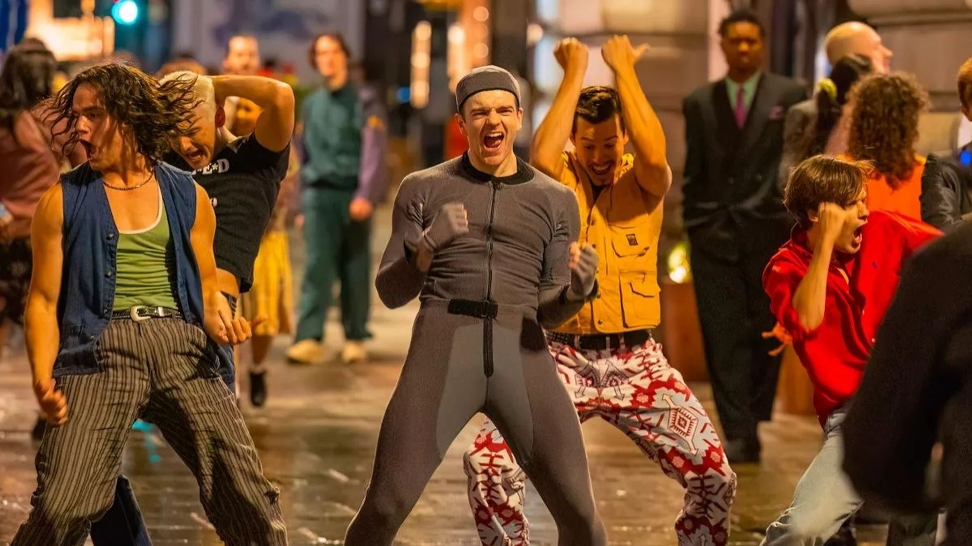 A man in a grey bodysuit for CGI purposes surrounded by a group of dancers depicting a young Take That, set on Regents Street