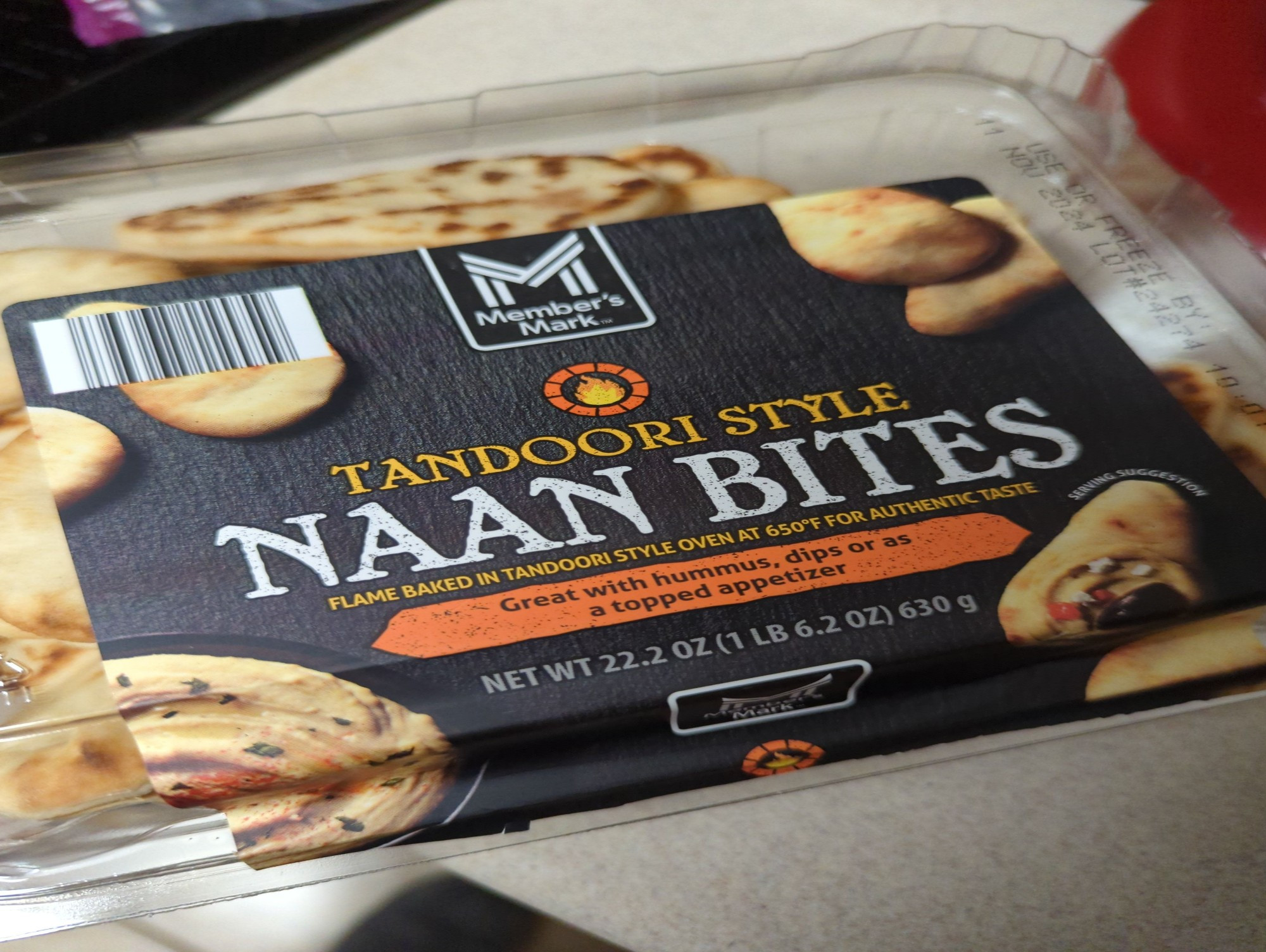 A package of Member's Mark Tandoori Style Naan Bites (clear plastic, dark grey label, pictures of tear-drop-shaped flatbread pieces and a small bowl of hummus)