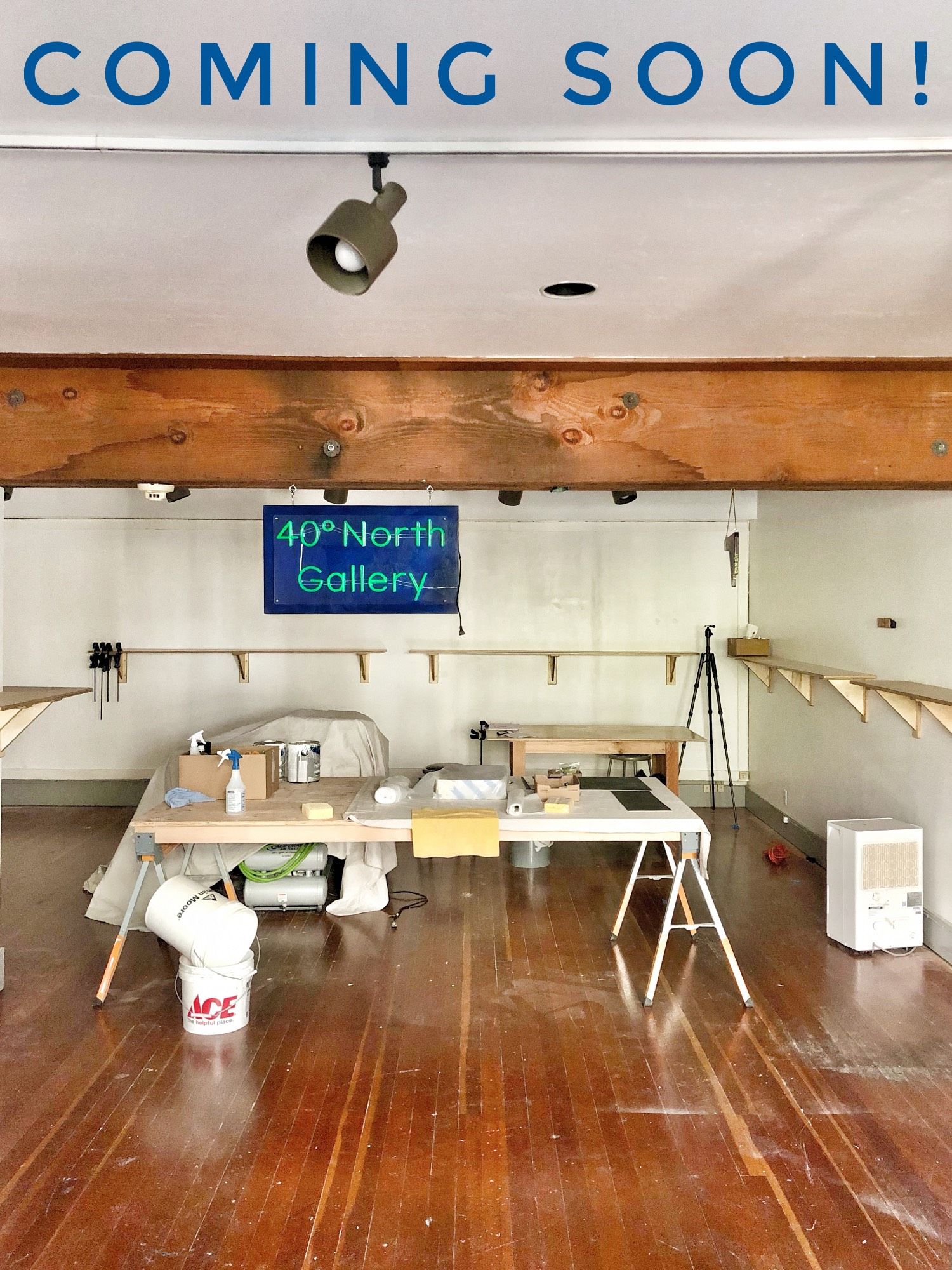 Interior of gallery space in progress, showing worktable ,  cleaning supplies, shelves underway, and the new neon sign: 40° North Gallery.