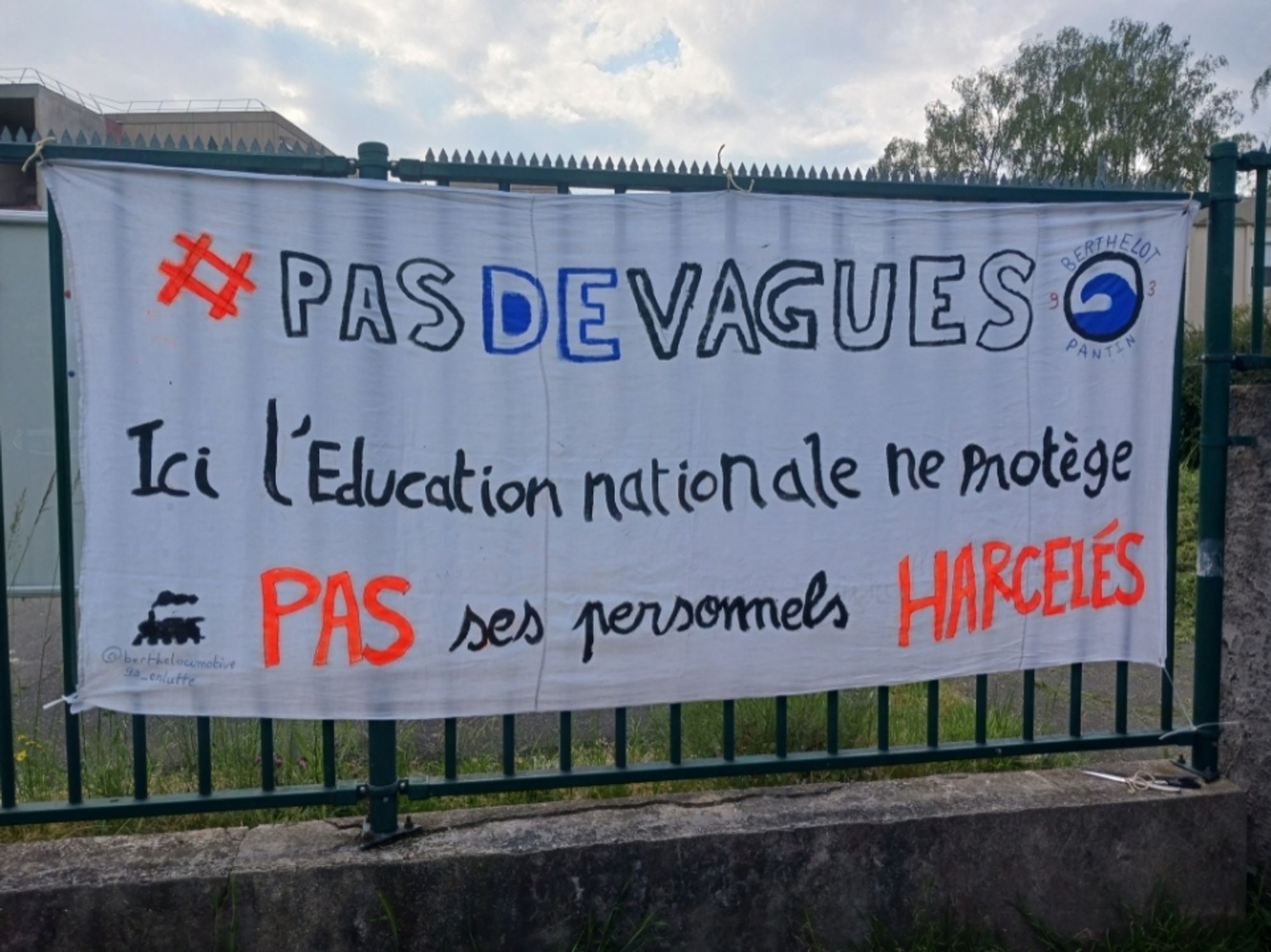 Banderole accrochée sur une grille avec écrit : "#pasdevagues ici l'éducation nationale ne protège pas ses personnels harcelés"