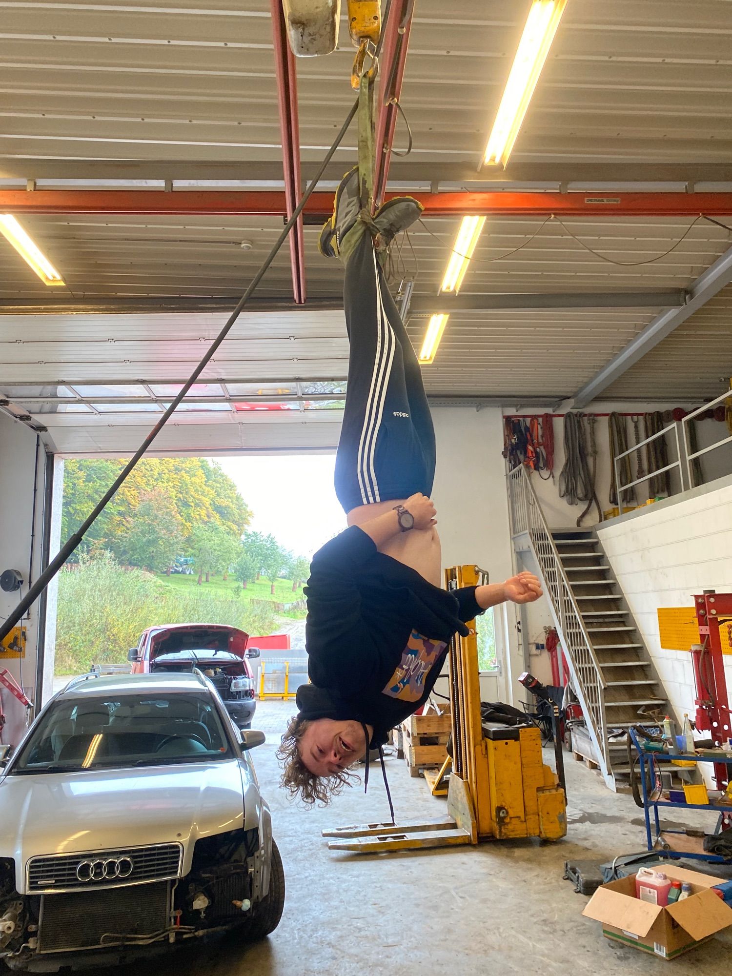 Ronny Burger hänging down from the ceiling in a very big garage. Kopfüber.