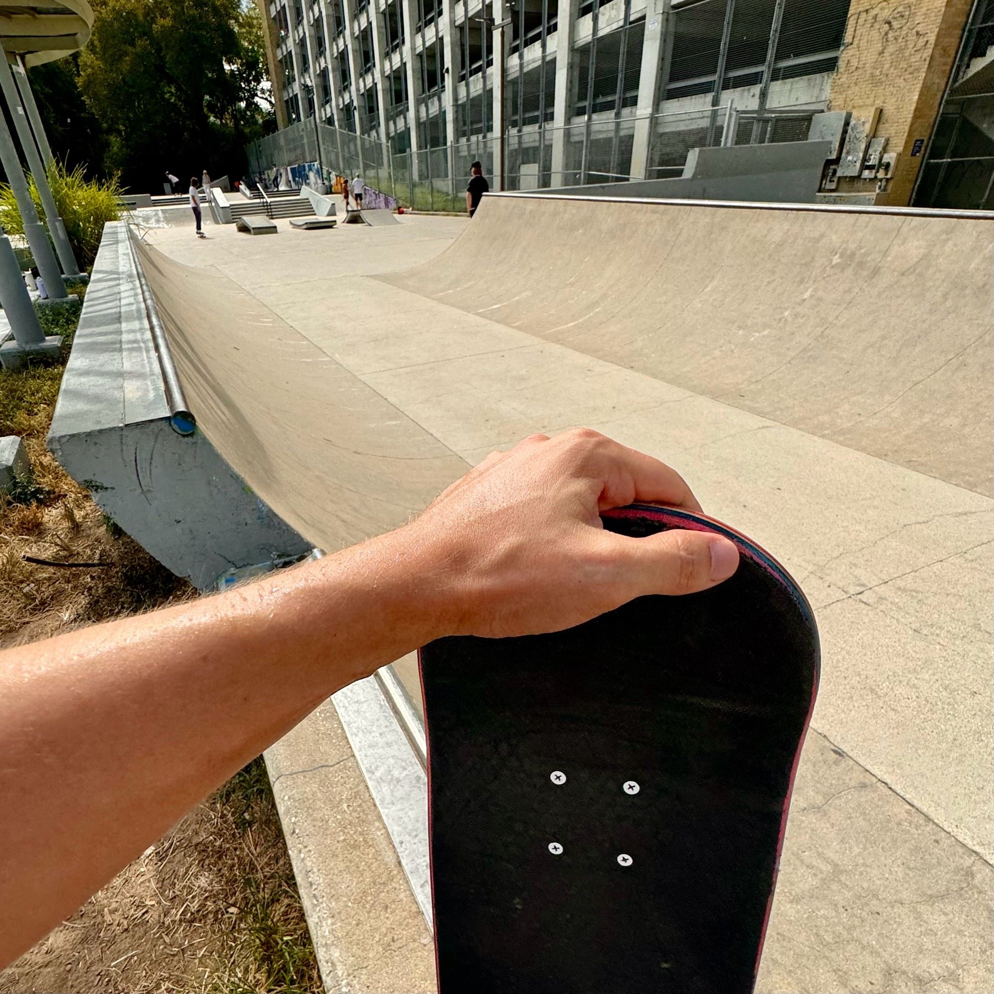 Pictured is my arm holding a skateboard with house park in the background