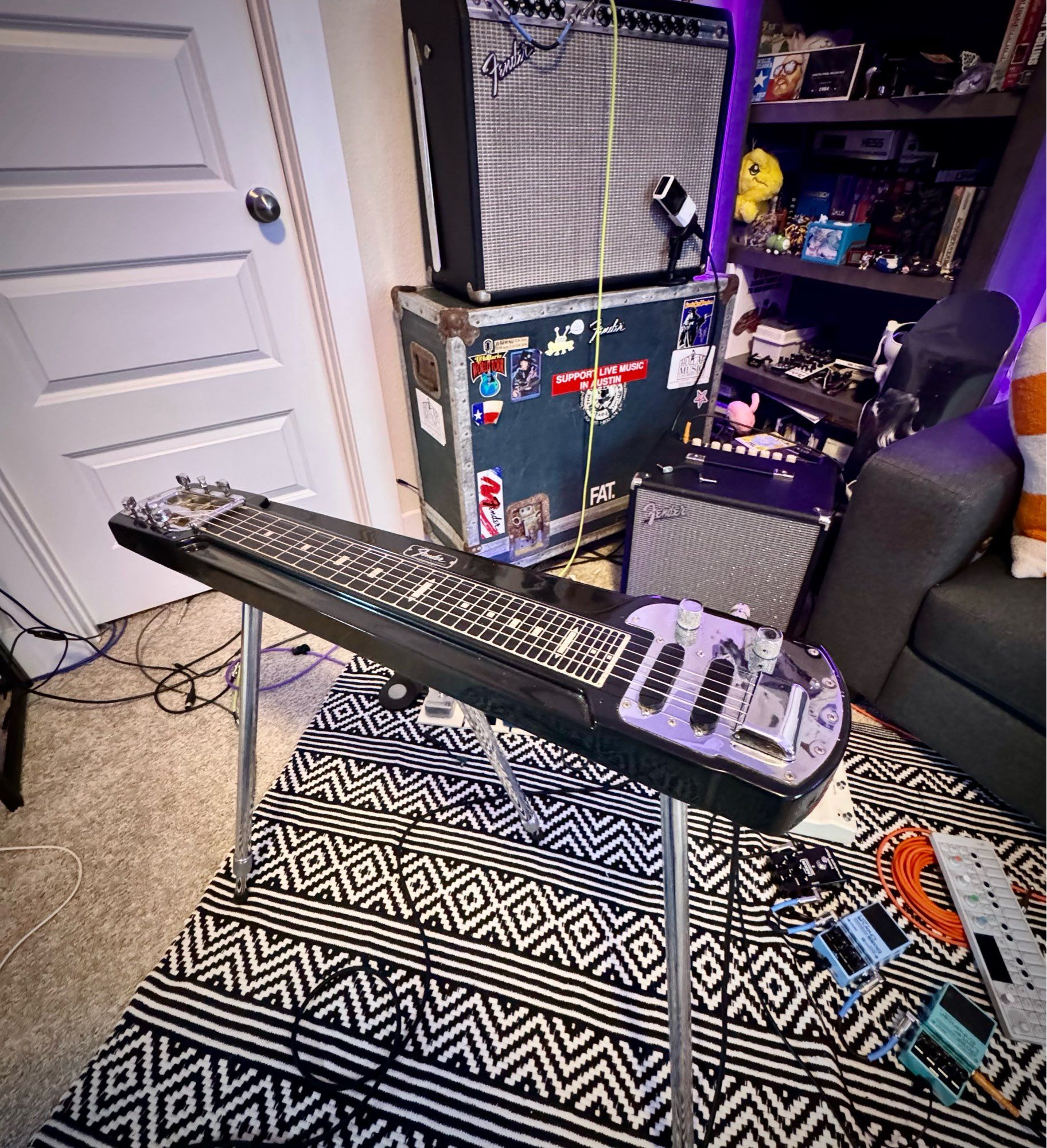 A black 1969 fender studio deluxe 6 string lap steel standing on its legs