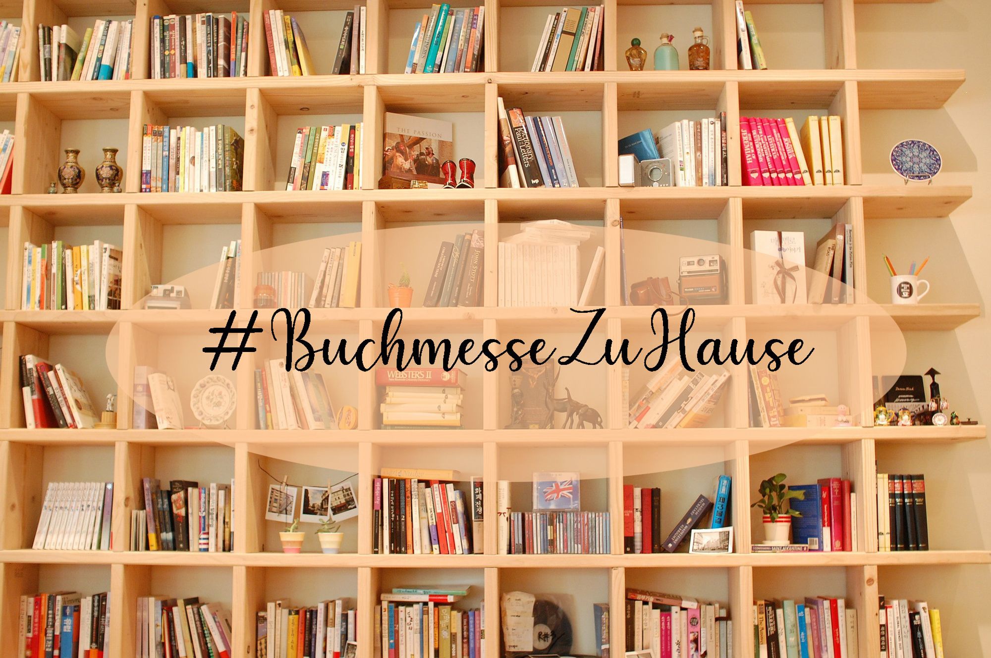 Foto eines großen Bücherregals mit vielen Büchern, mittig ein Oval mit der Aufschrift #BuchmesseZuHause