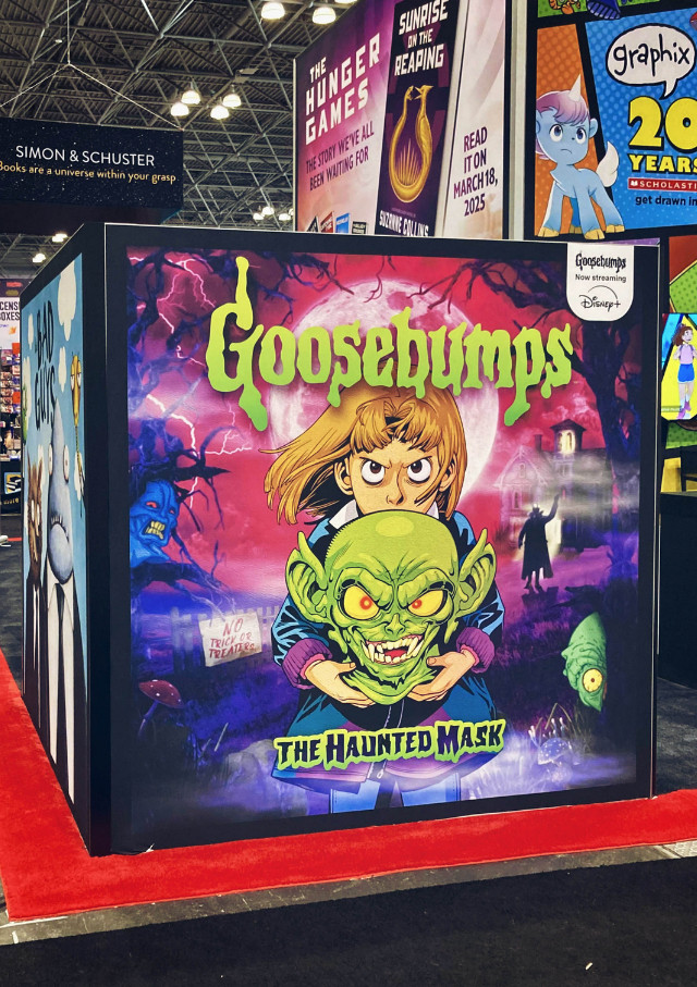 a large display at New York City Comic Con. On one side is printed the cover art for Goosebumps Graphix's The Haunted Mask. The cover art is overlaid on some "creepy" graphic art by an unknown designer.