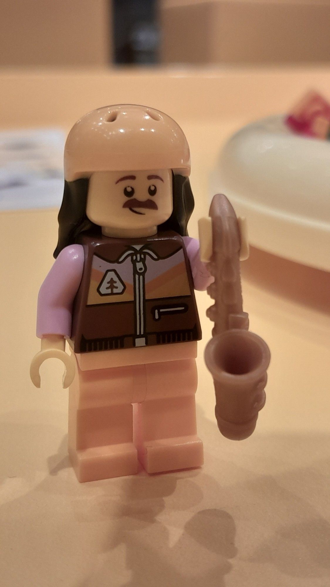 Bonequinho de lego que era pra ser o Ambrose da banda King Gizzard and the Lizard Wizard. Pontos chaves de identificação; cabelo grande, bigode e saxofone na mão esquerda.