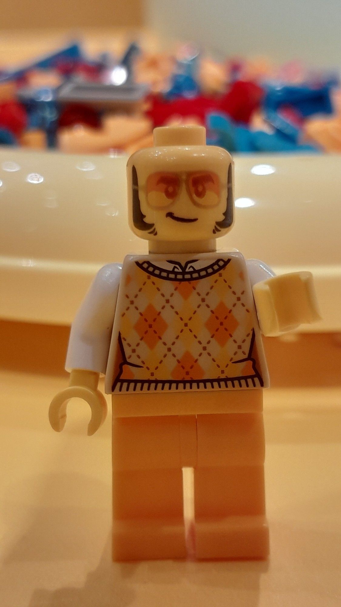 Bonequinho de lego que era pra ser o Elton John, talvez a única coisa parecida seja os óculos escuros e umas costeletas 😭.