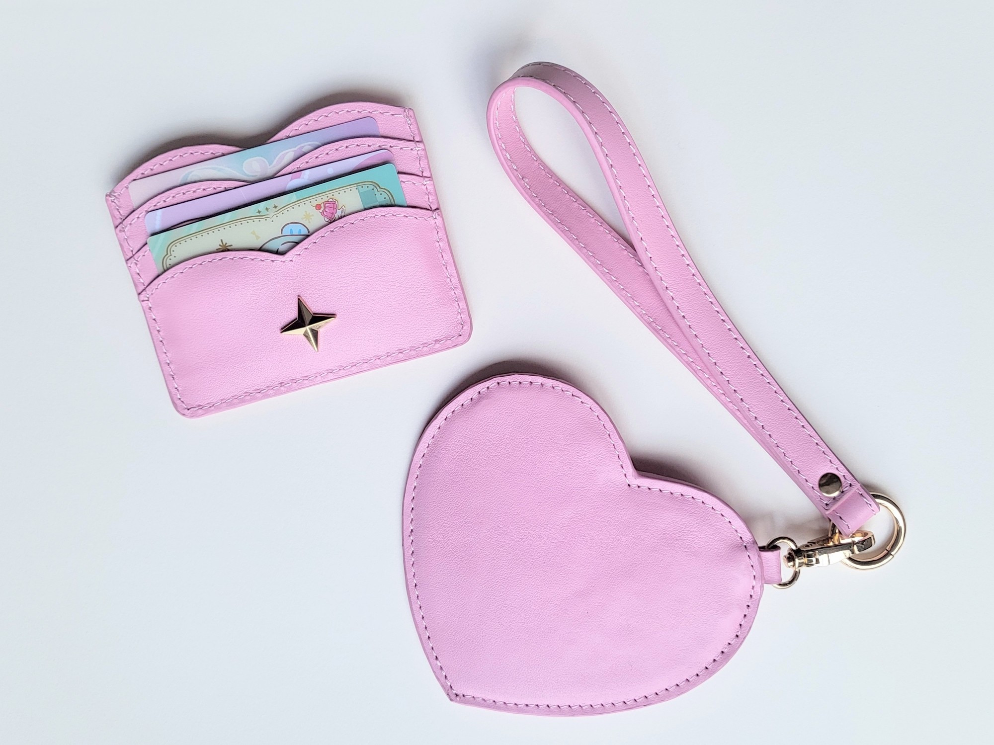 A scalloped card holder wallet and a heart shaped coin purse with a wrist strap.