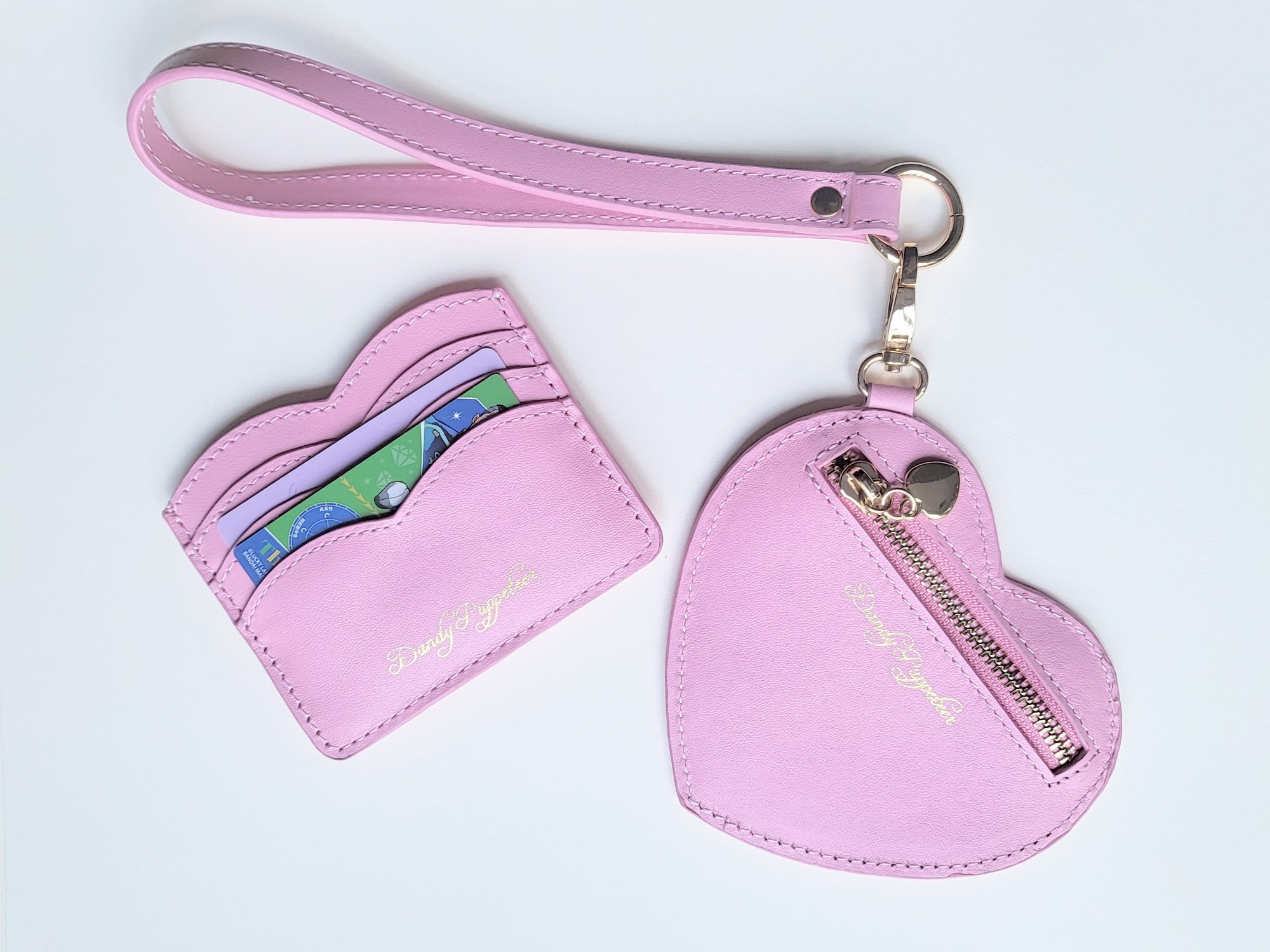 A scalloped card holder wallet and a heart shaped coin purse with a wrist strap.