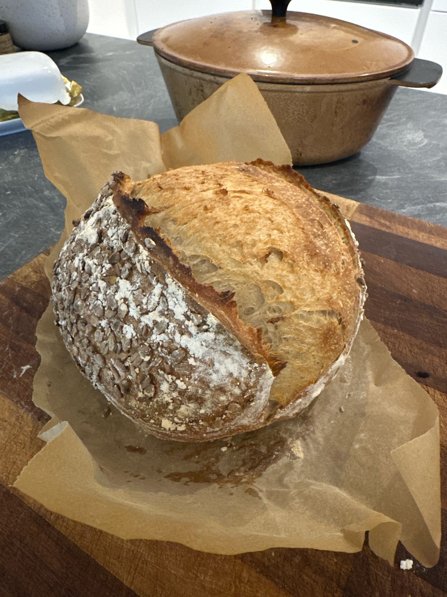 A freshly baked loaf. It’s on parchment paper having just been removed from the casserole dish which is visible in the background.