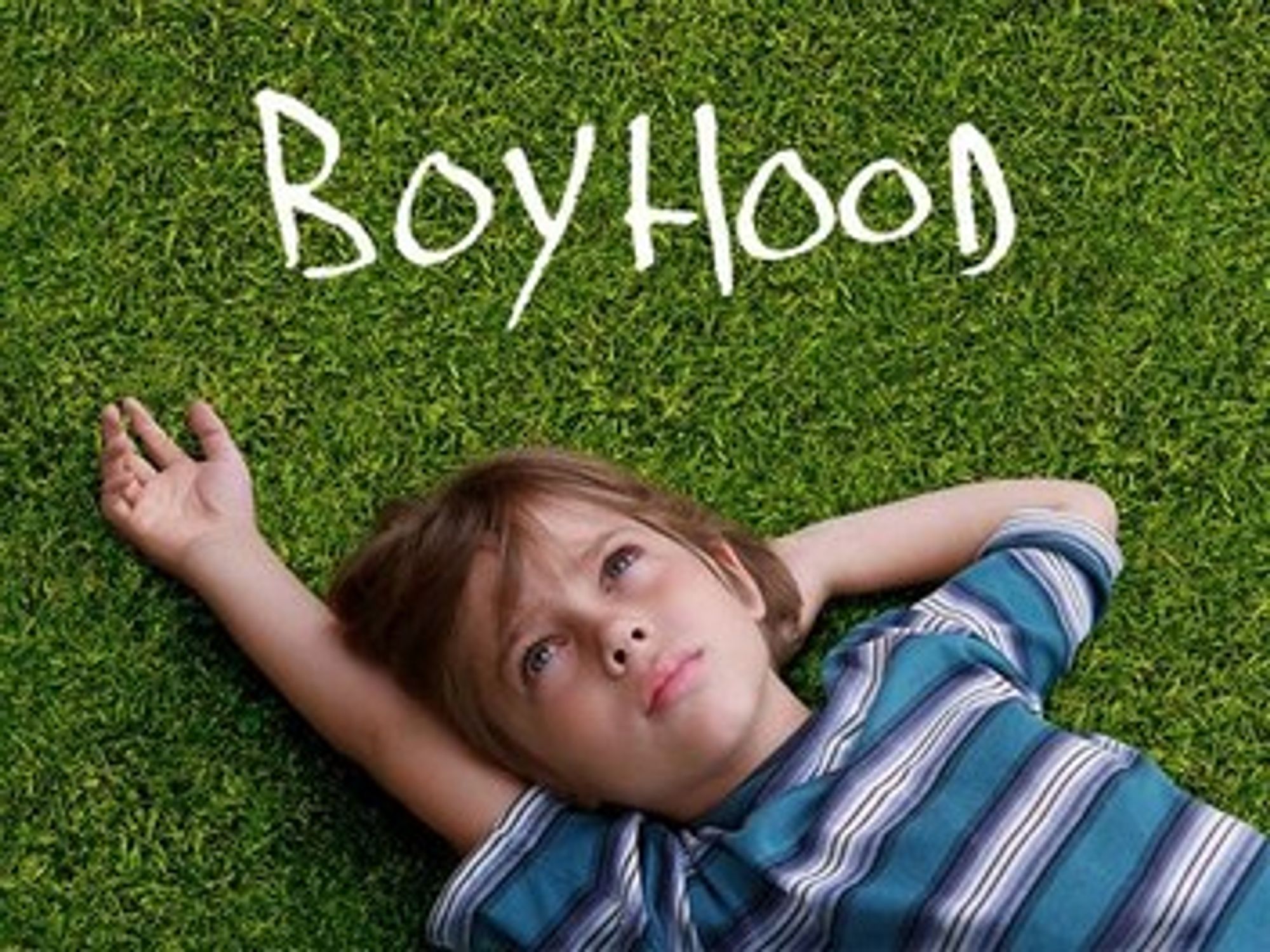 an image from the movie Boyhood which has a little boy laying on the ground in a striped shirt with his arm held up.