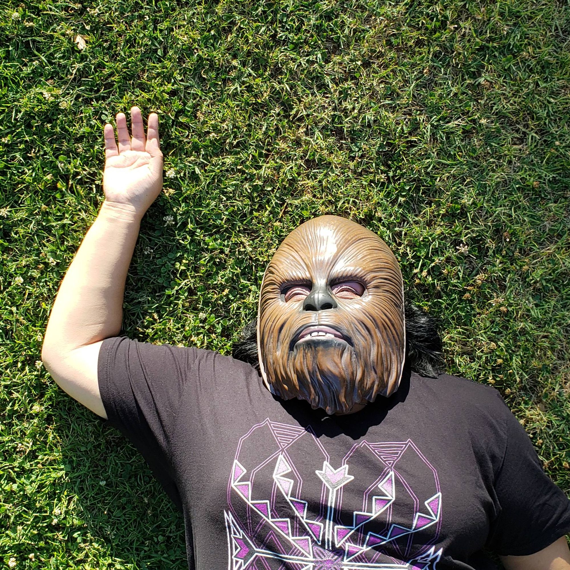 A photo of Johnnie Jae wearing a Wookie mask laying on the ground with her arm held up