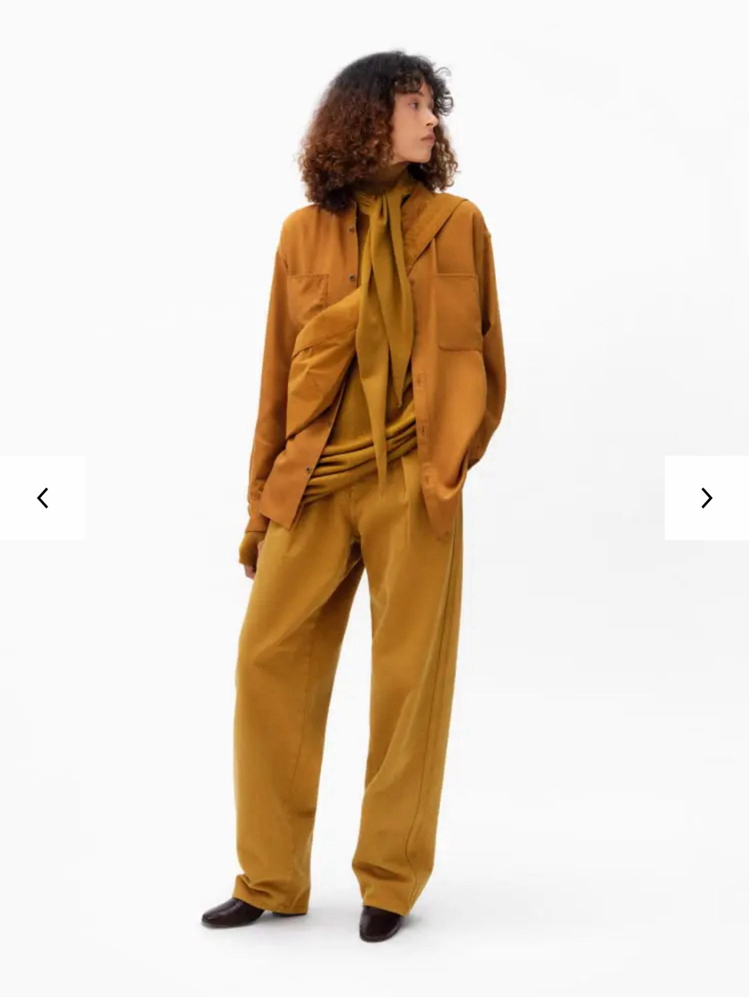 An image from the Uniqlo website featuring a tall model woman wearing an all mustard yellow outfit (jacket, scarf, bag, top, trousers all very similar shade)