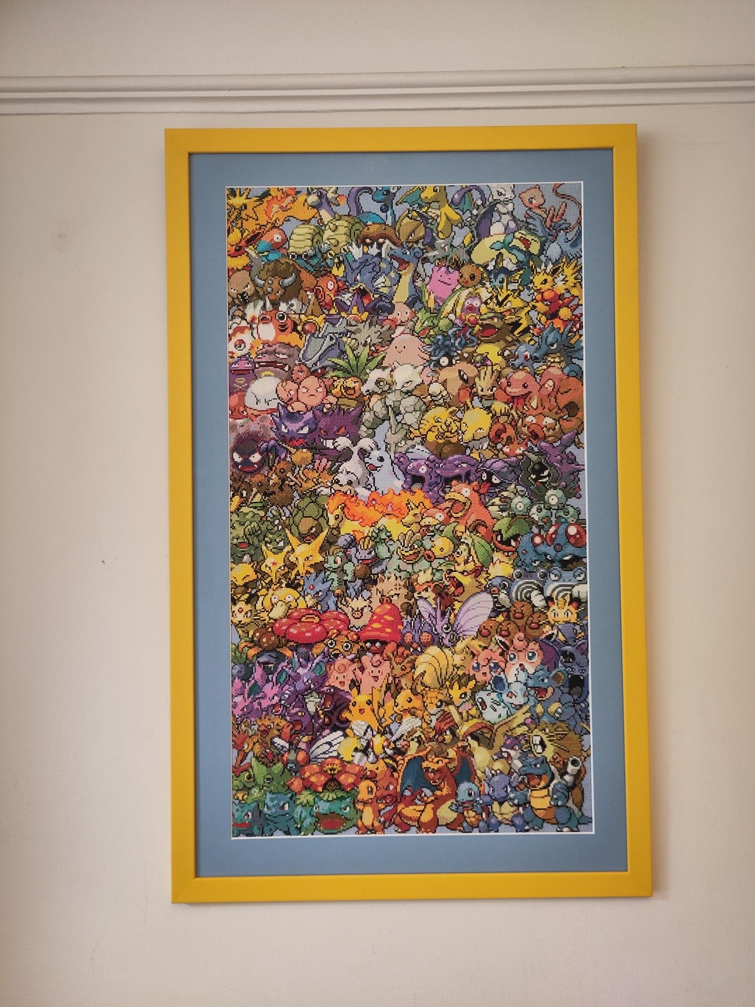 Huge cross-stitch of all 151 Generation 1 Pokémon overlapping each other, in a bright yellow frame with a light blue mount.