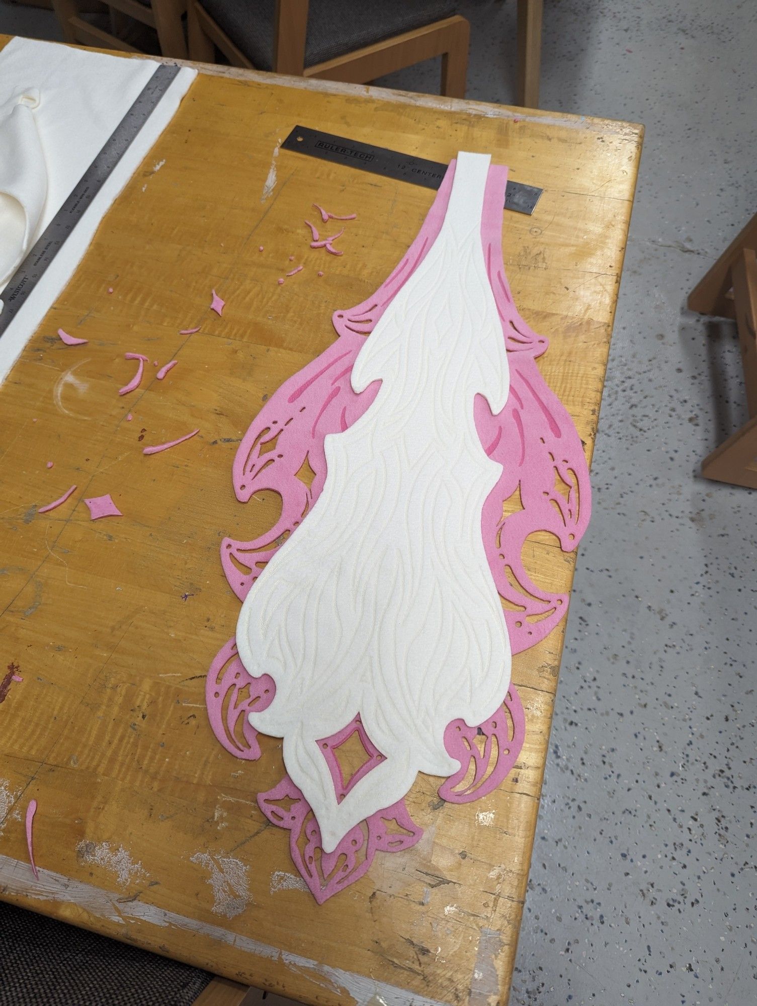 A photo of cut out pieces of pink and white fabric that match the design in the previous image