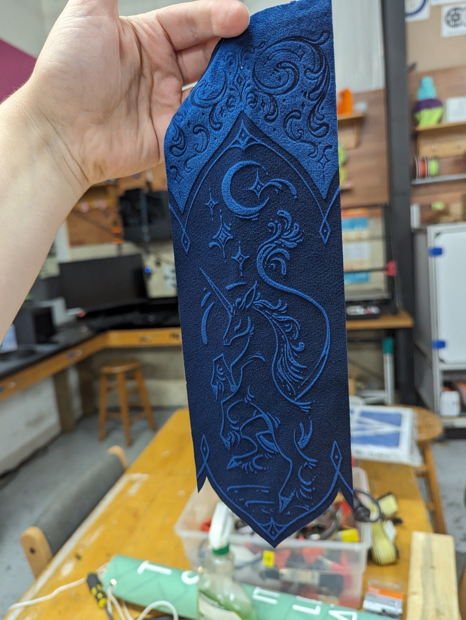 Full sized prototype of blue velvet ribbon tail with ornamental unicorn design