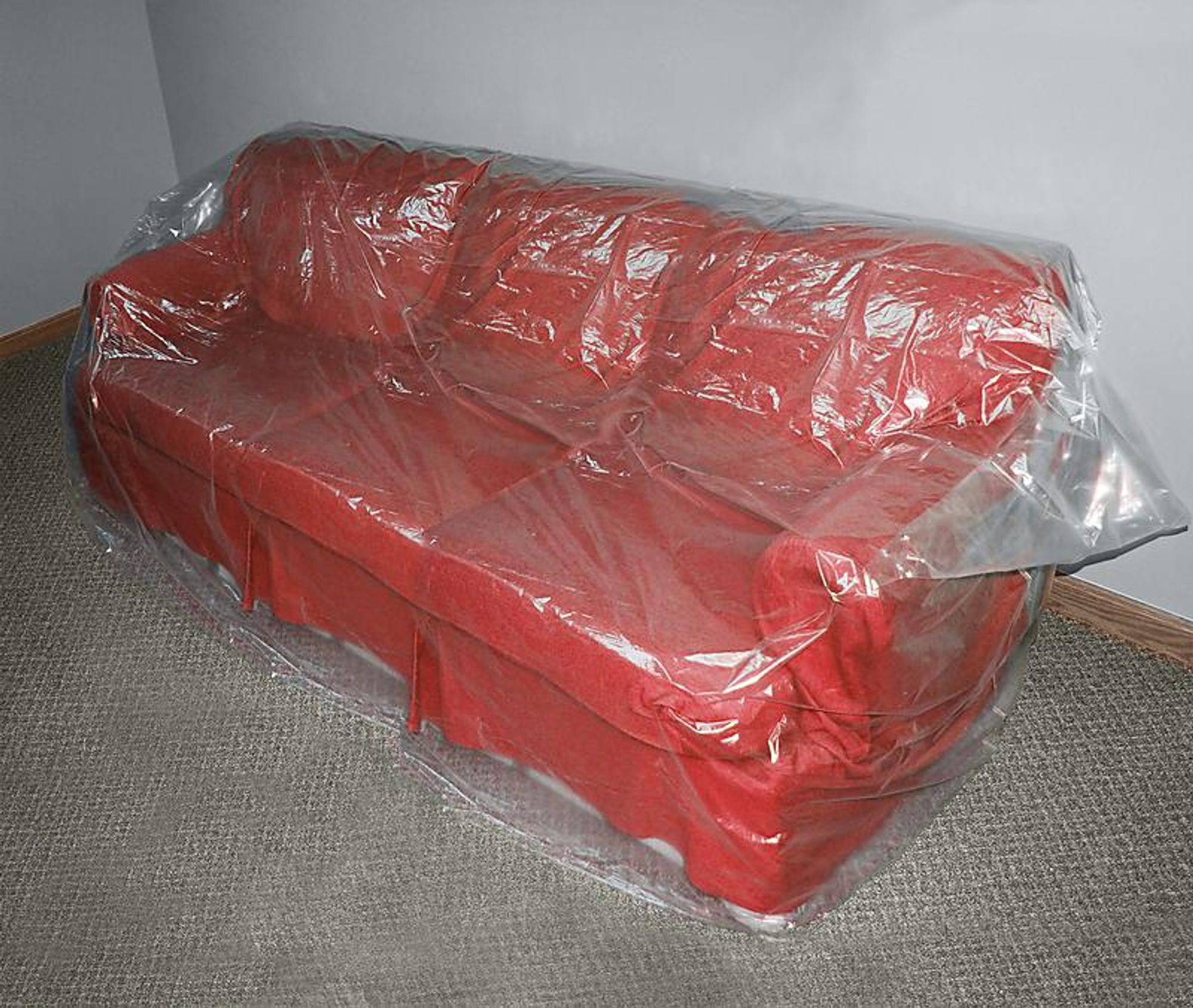 Photo of a red couch wrapped in plastic.