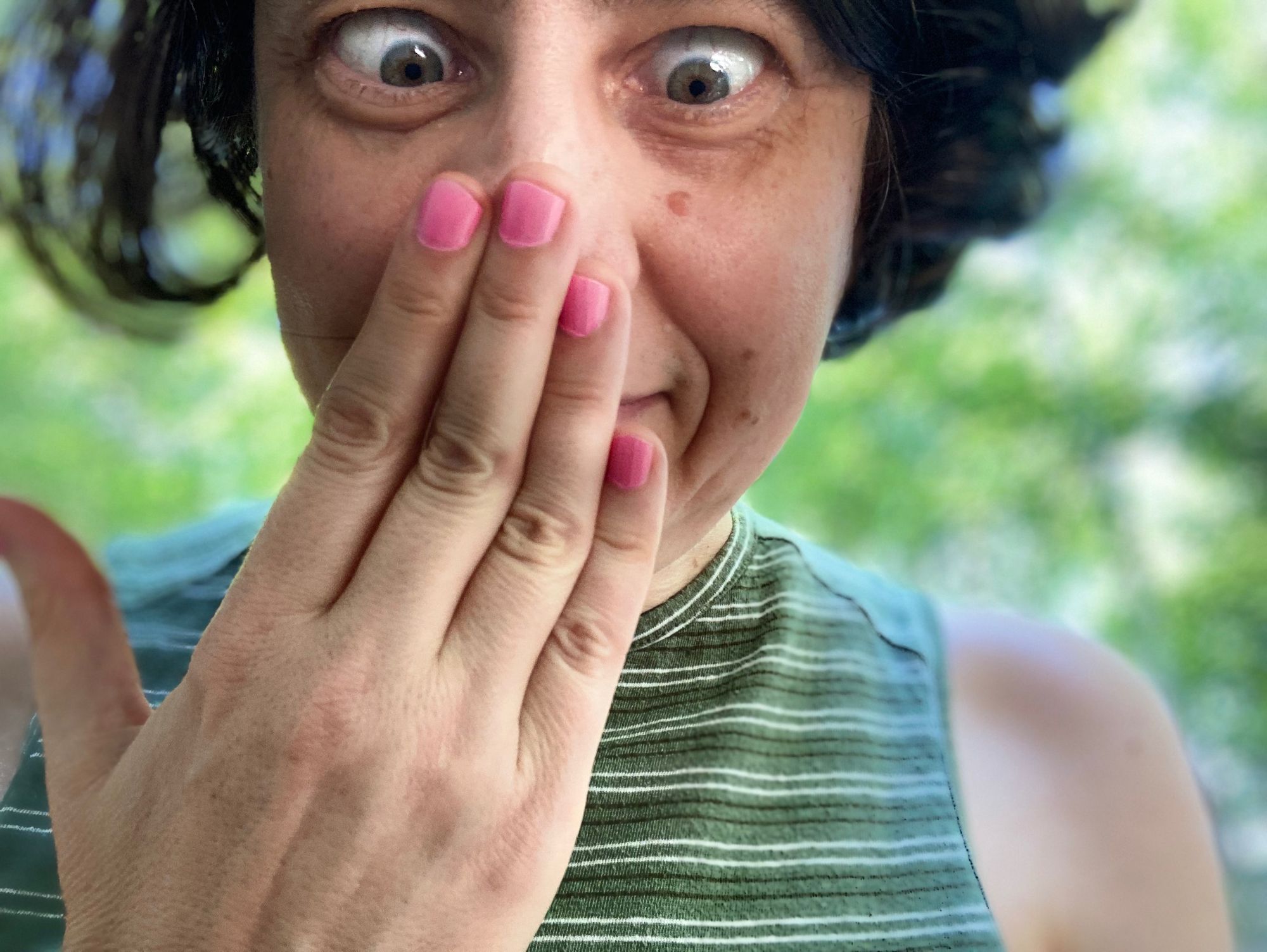 Author--a white woman with short, dark hair--looking cross-eyed at her pink fingernails, pressed to her nose.