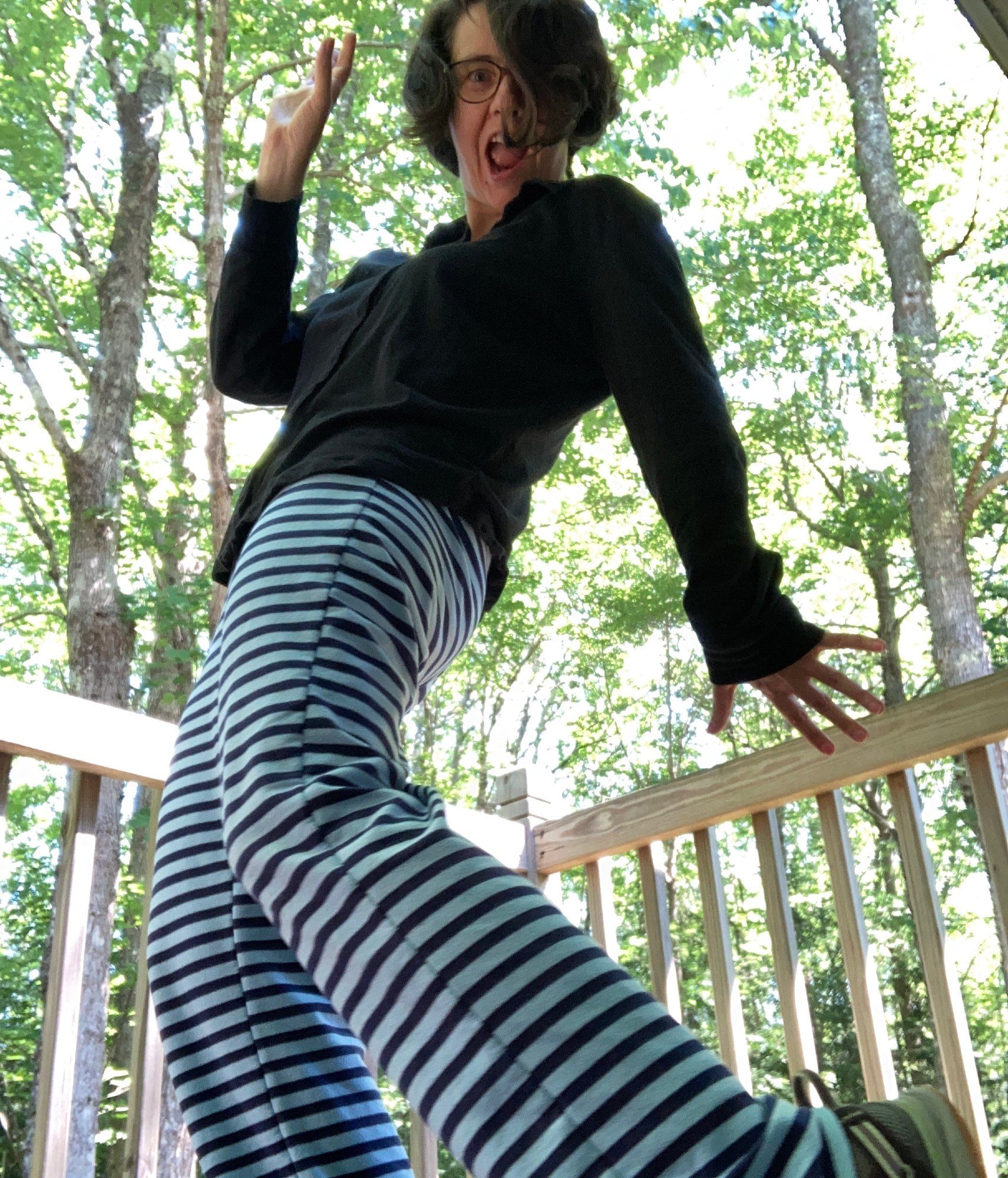 Swinging sideways pose in blue and black striped pants, out of my deck with the canopy of trees above me.