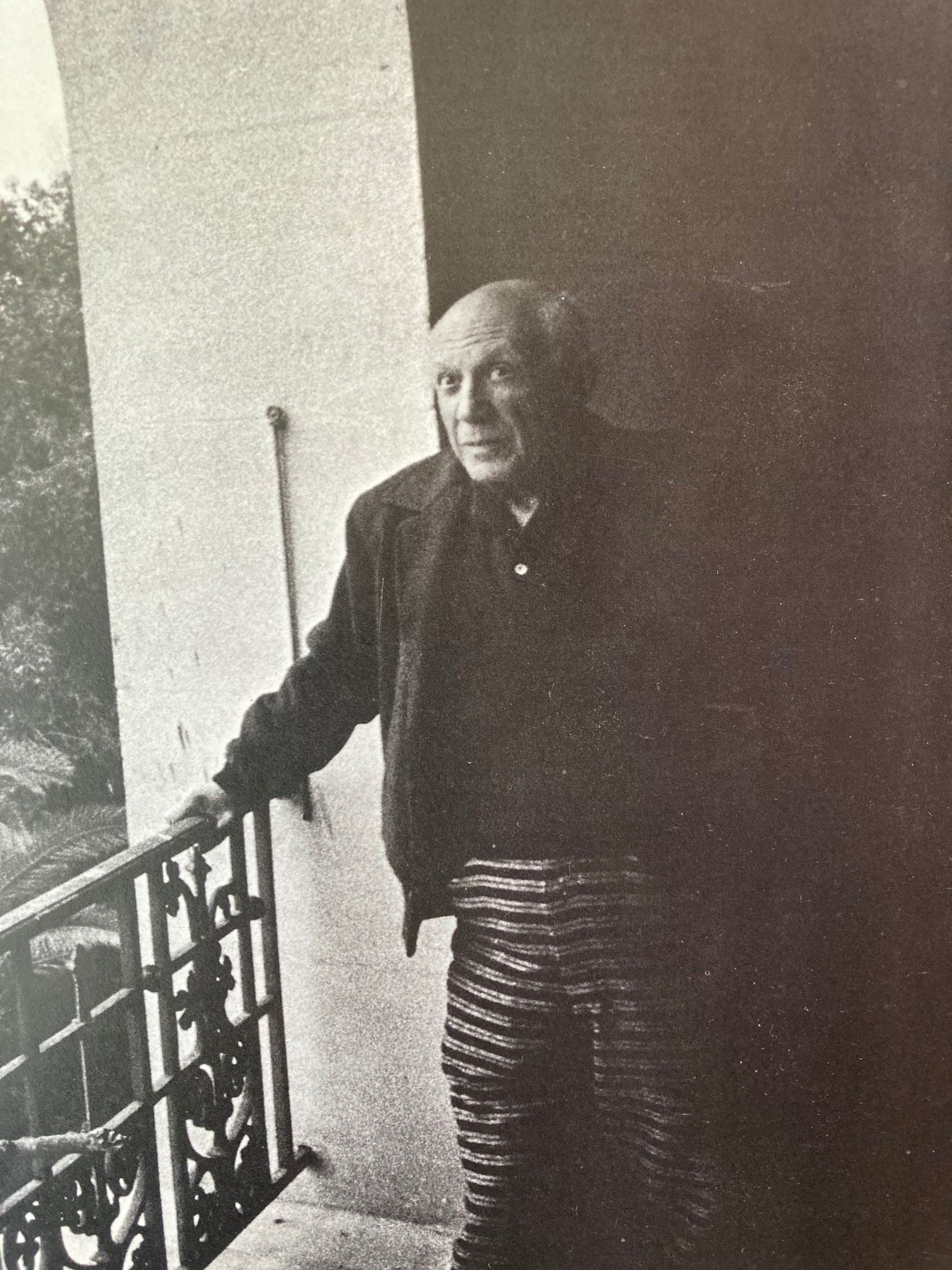 Picasso in striped pants on the balcony of his villa.