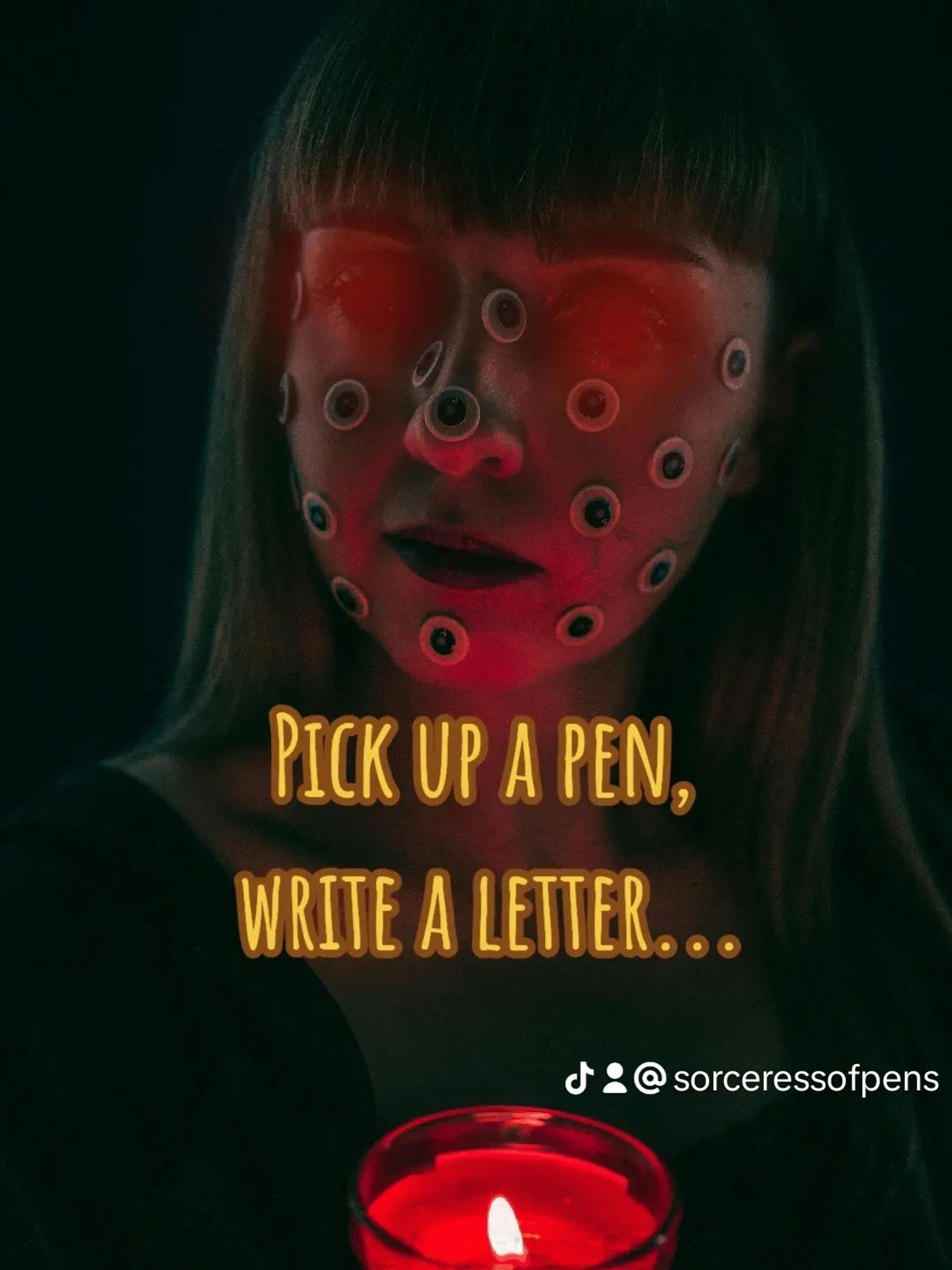 Woman is lit red by a candle. She has a handful of eyes all over her face and her two real ones are glowing red. Text reads: Pick up a pen, write a letter.