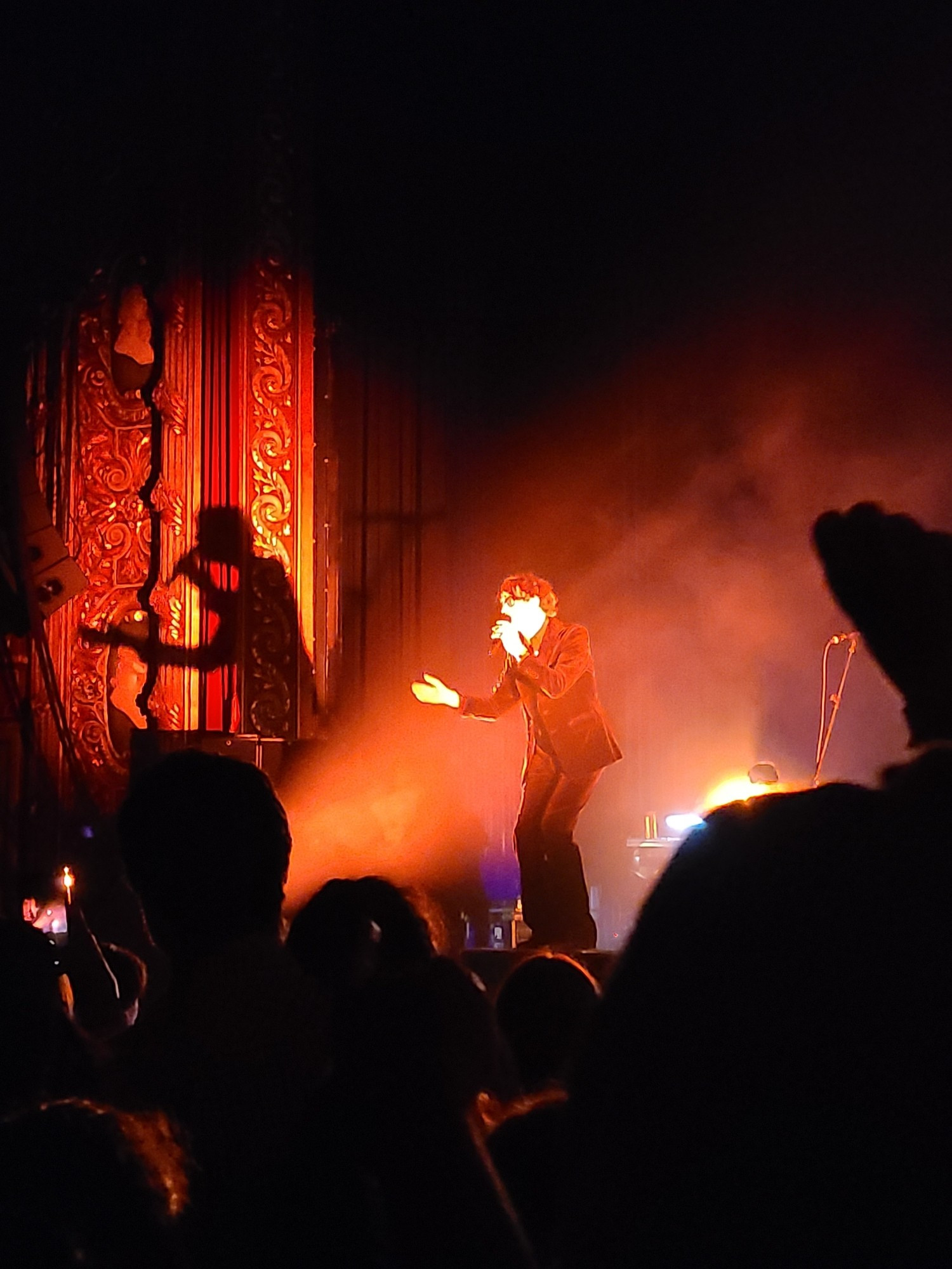 Jarvis Cocker singing in red light, his shadow on the wall behind him