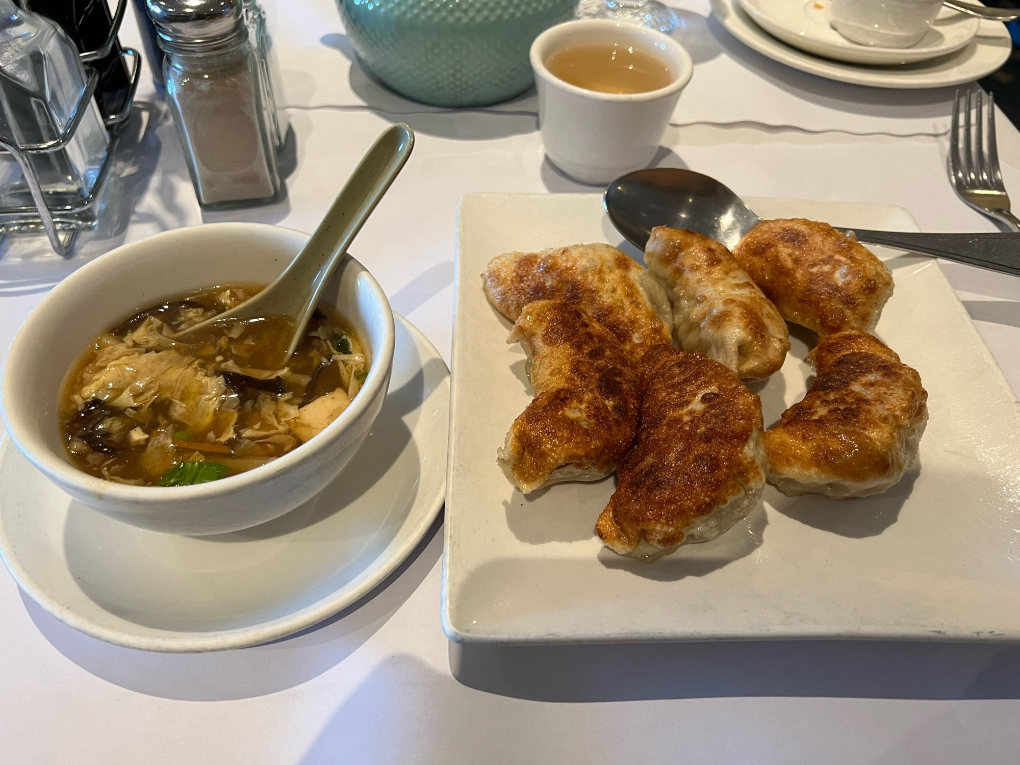 Hot & sour soup in a small bowl and 6 fried potstickers on a plate.