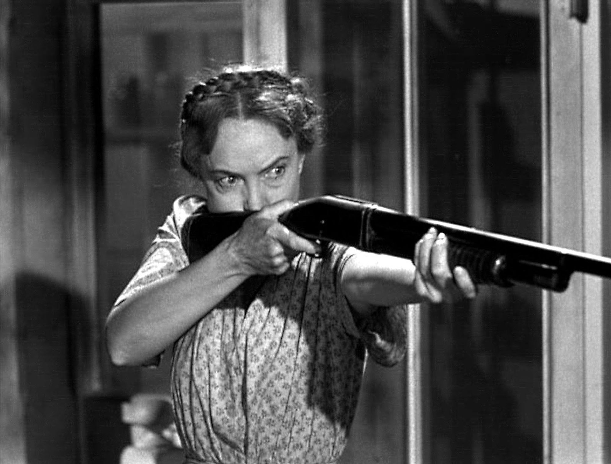 Lillian Gish as Rachel Cooper, a spinster who takes in children, pointing a shotgun straight at someone outside of the view of the camera.